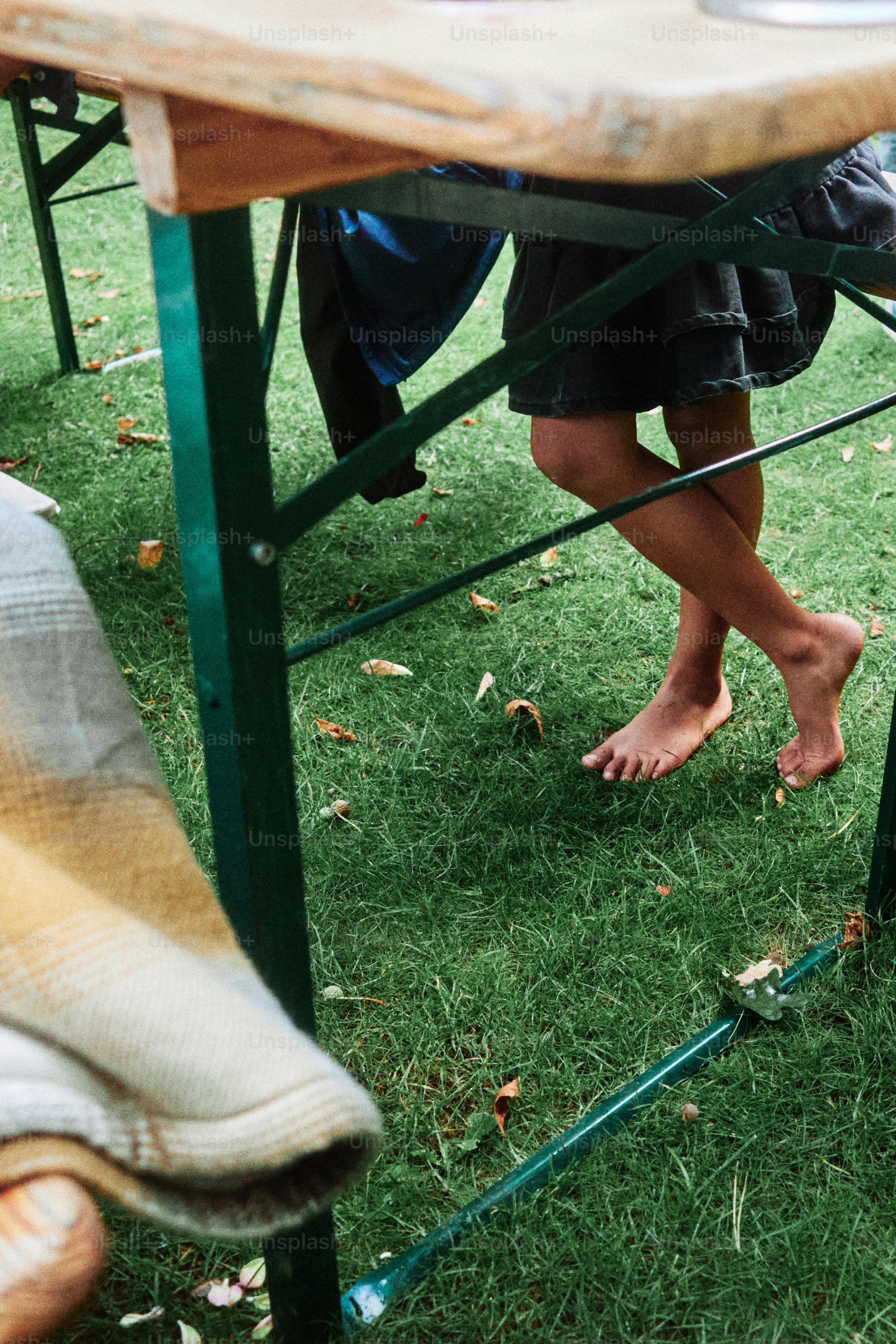 Anak bertelanjang kaki berdiri di atas rumput dekat meja