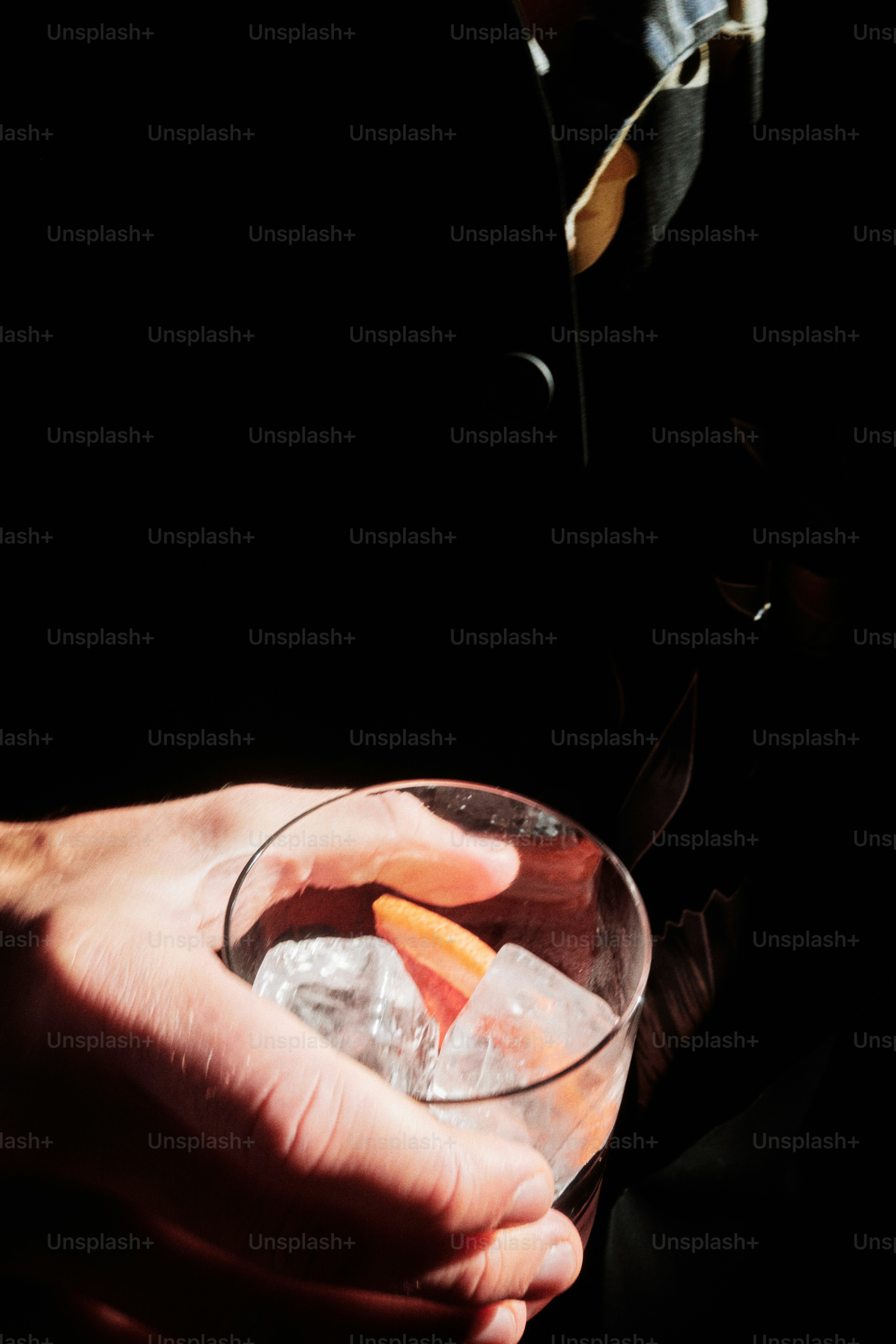 Un homme tenant un cocktail avec de la glace et une tranche d’orange