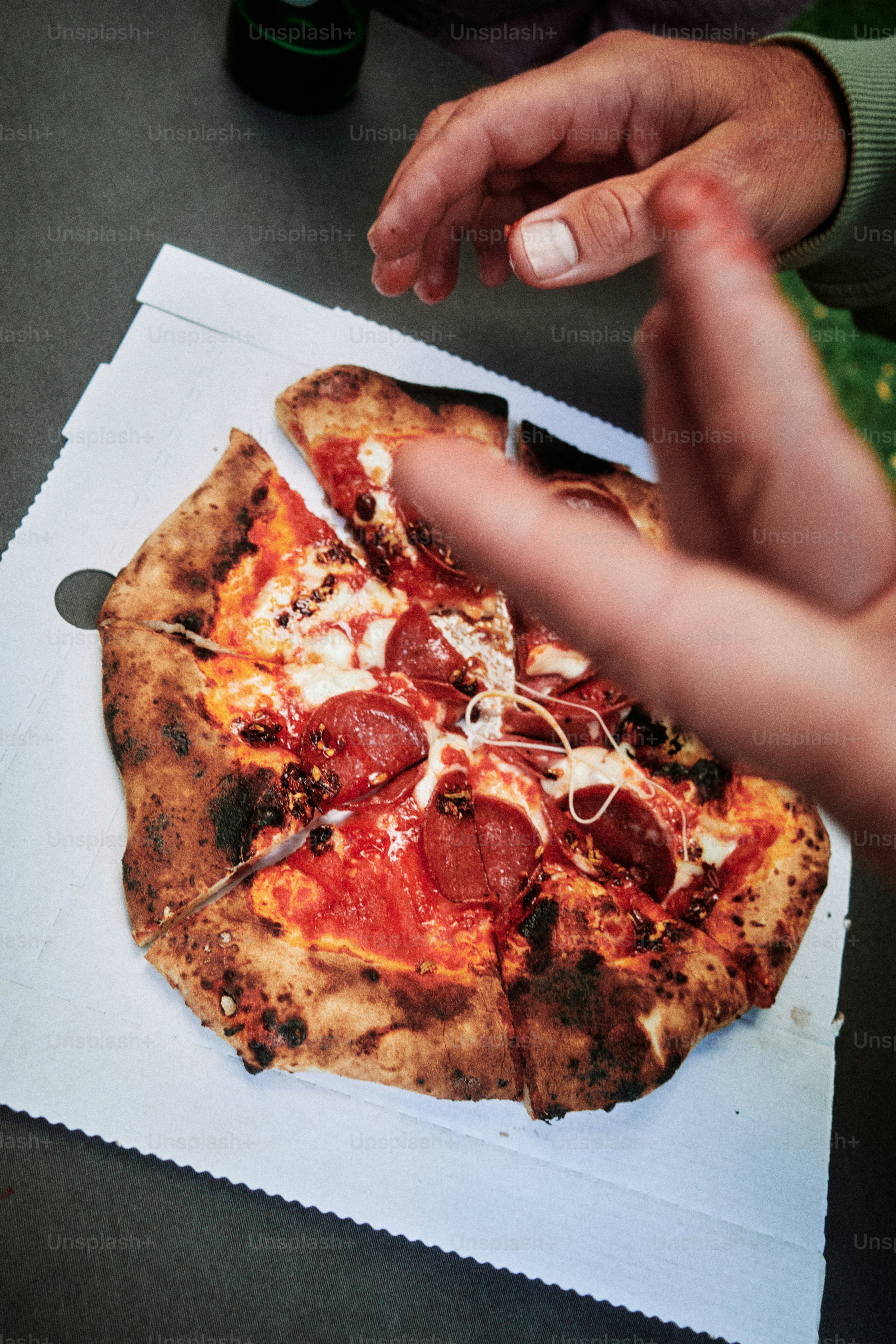 Pizza al pepperoni in una scatola con le mani che si protendono