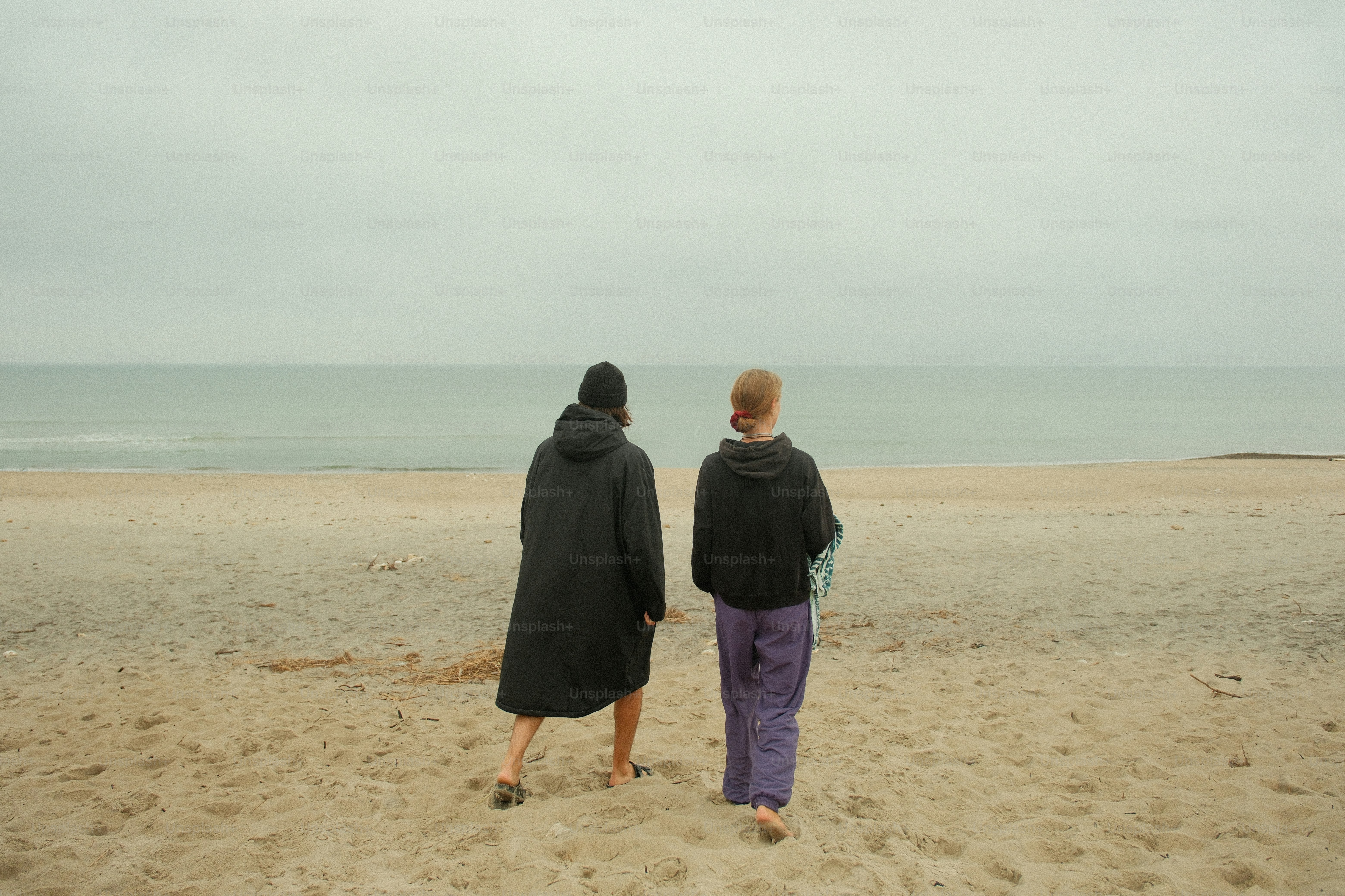 couple-walking-towards-the-ocean-on-a-cloudy-day-photo-beach-image-on