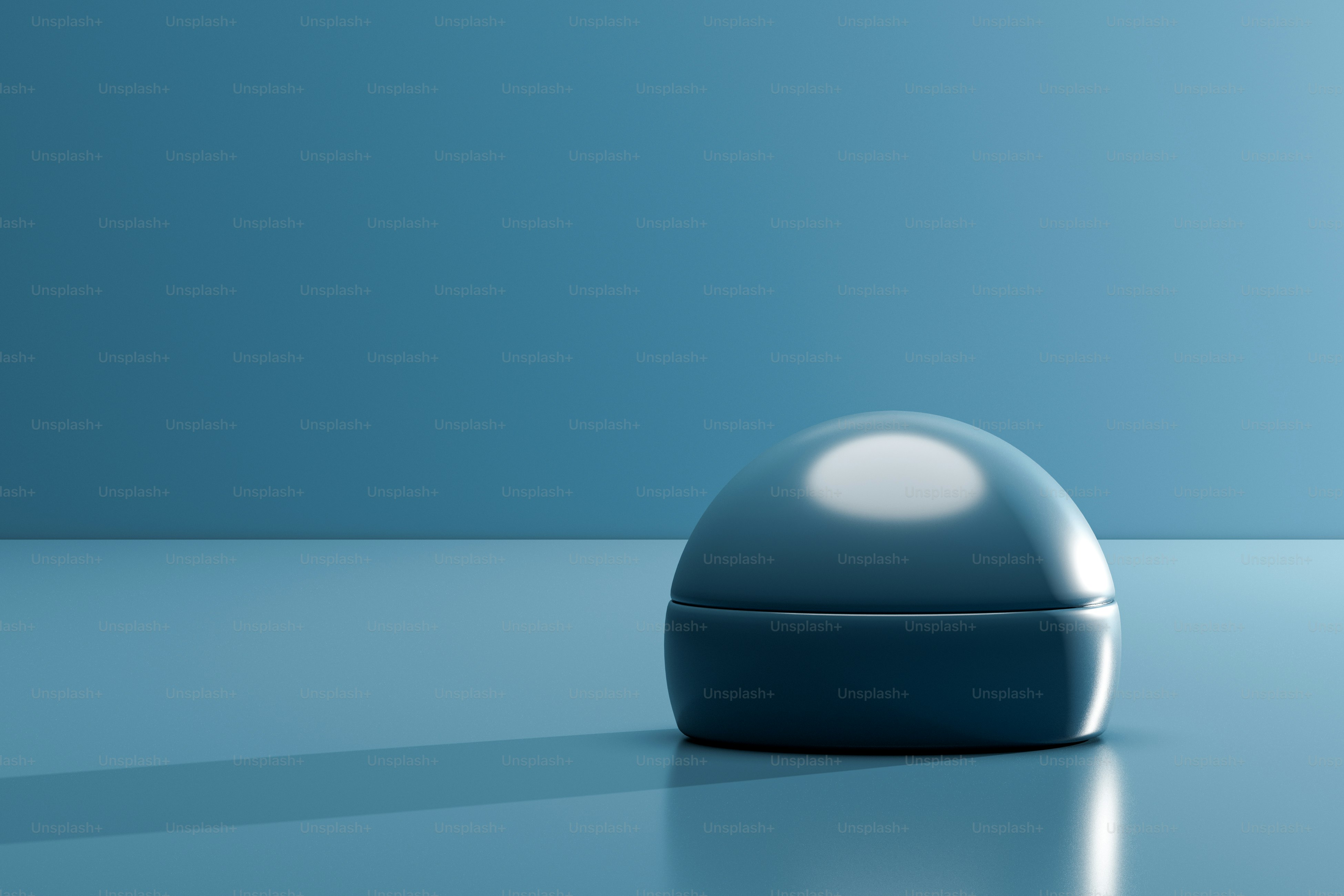 반사되는 표면 위에 매끄럽고 짙은 파란색 둥근 상자가 있었다.