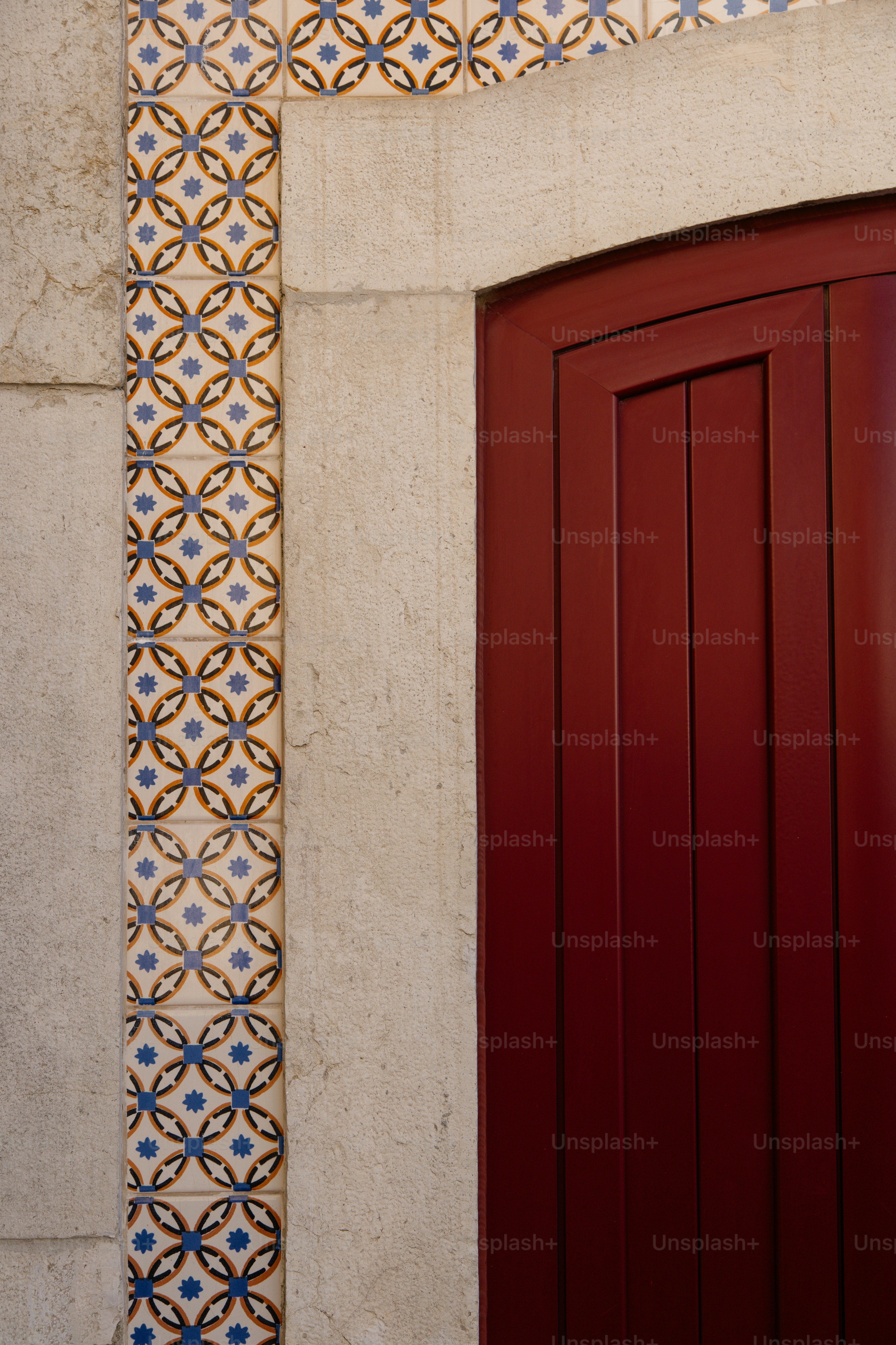 Rote Tür mit dekorativen Fliesen und Steinrahmen