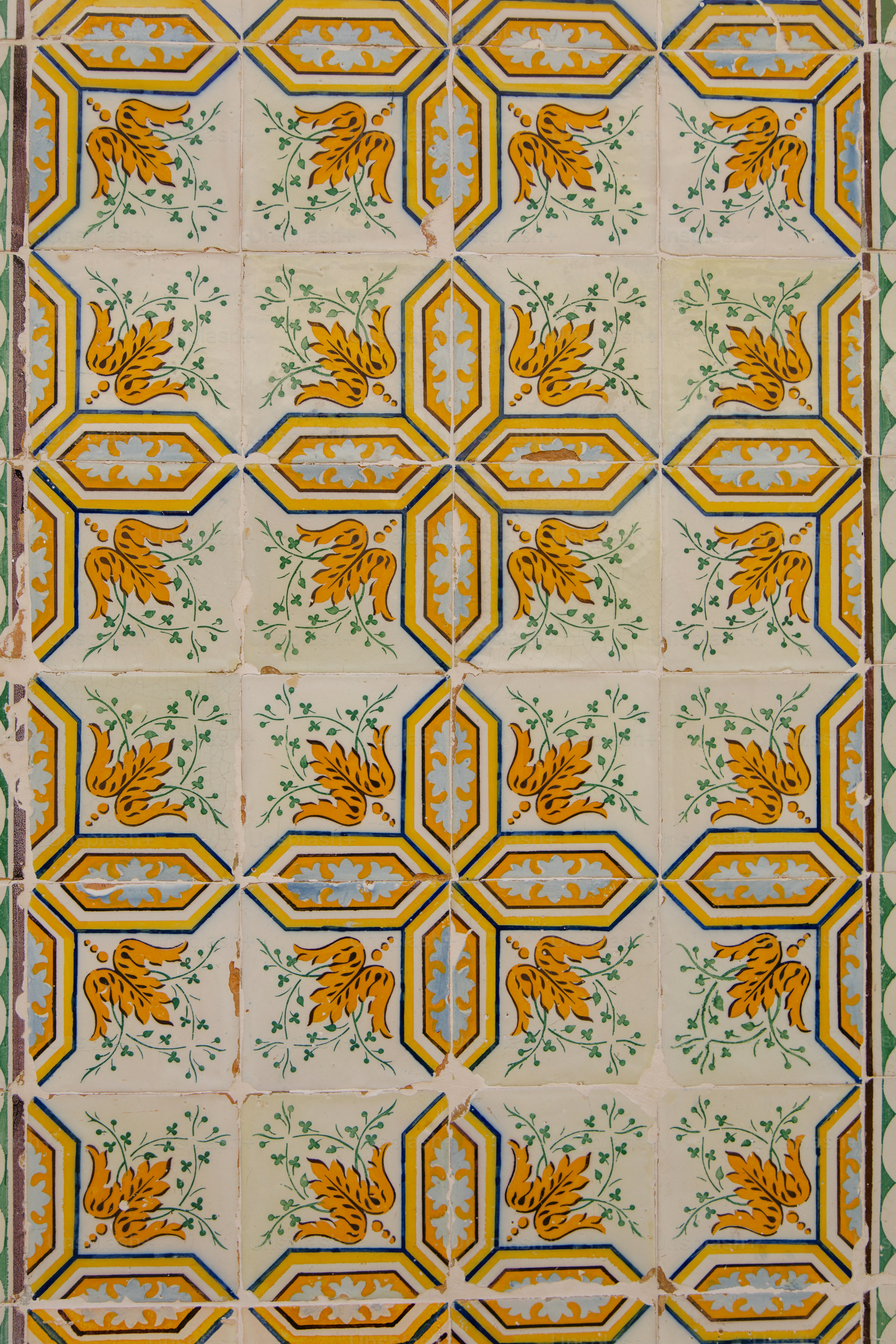 Verziertes gelb-blaues Kachelmuster mit Vögeln.