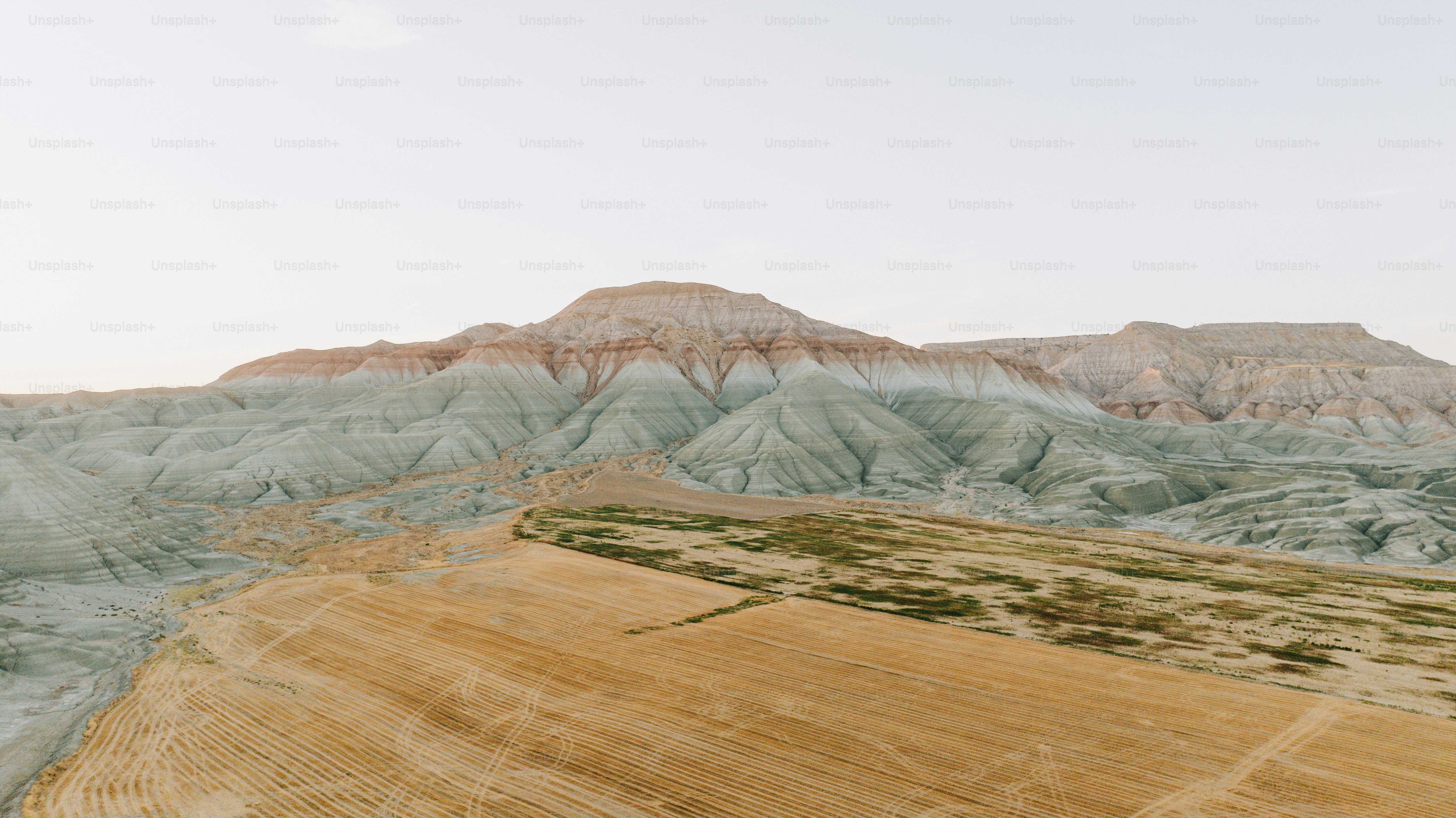 Colorful hills and a dry field under a pale sky