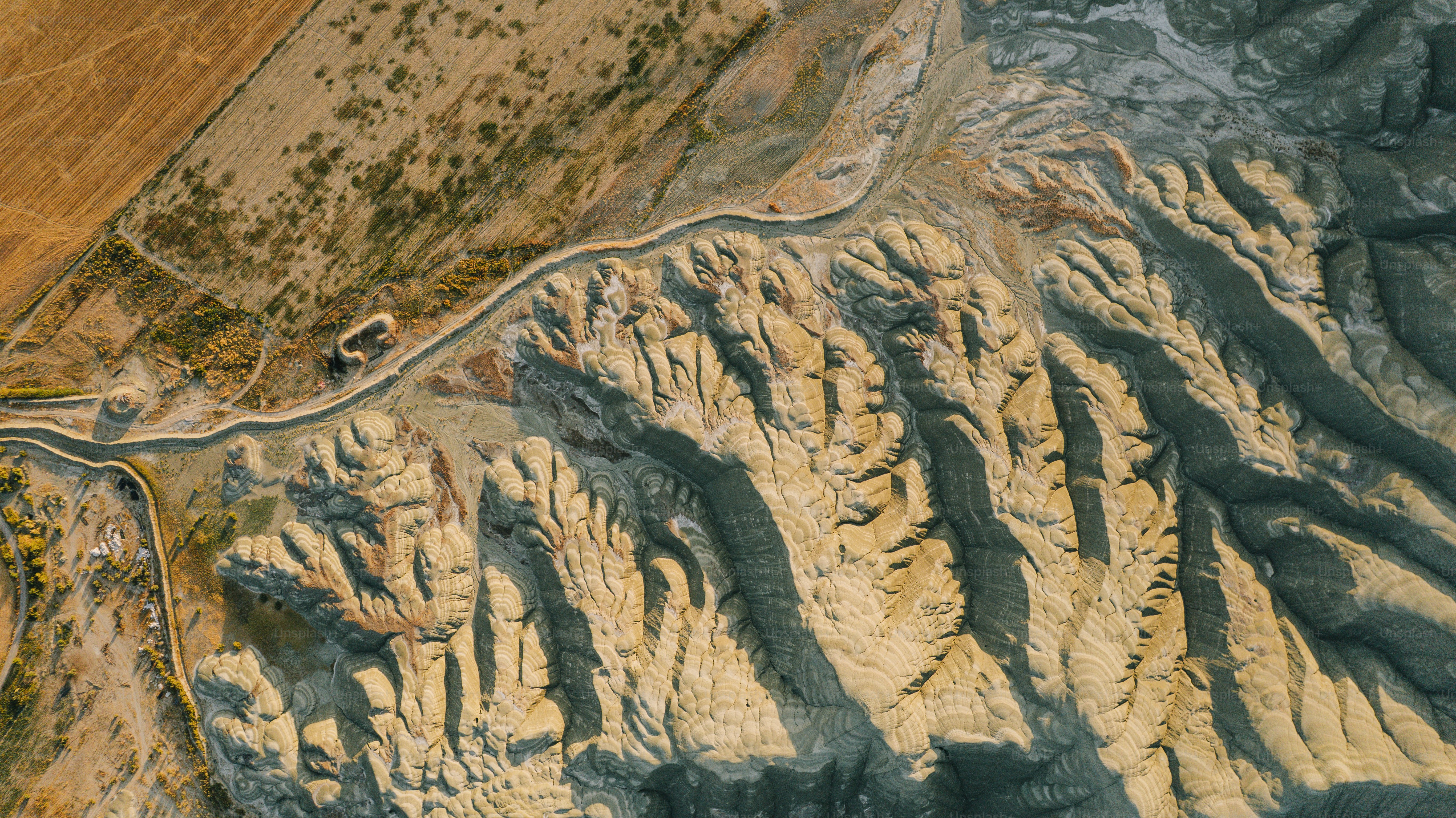 Aerial view of a winding road through arid, eroded landscape.