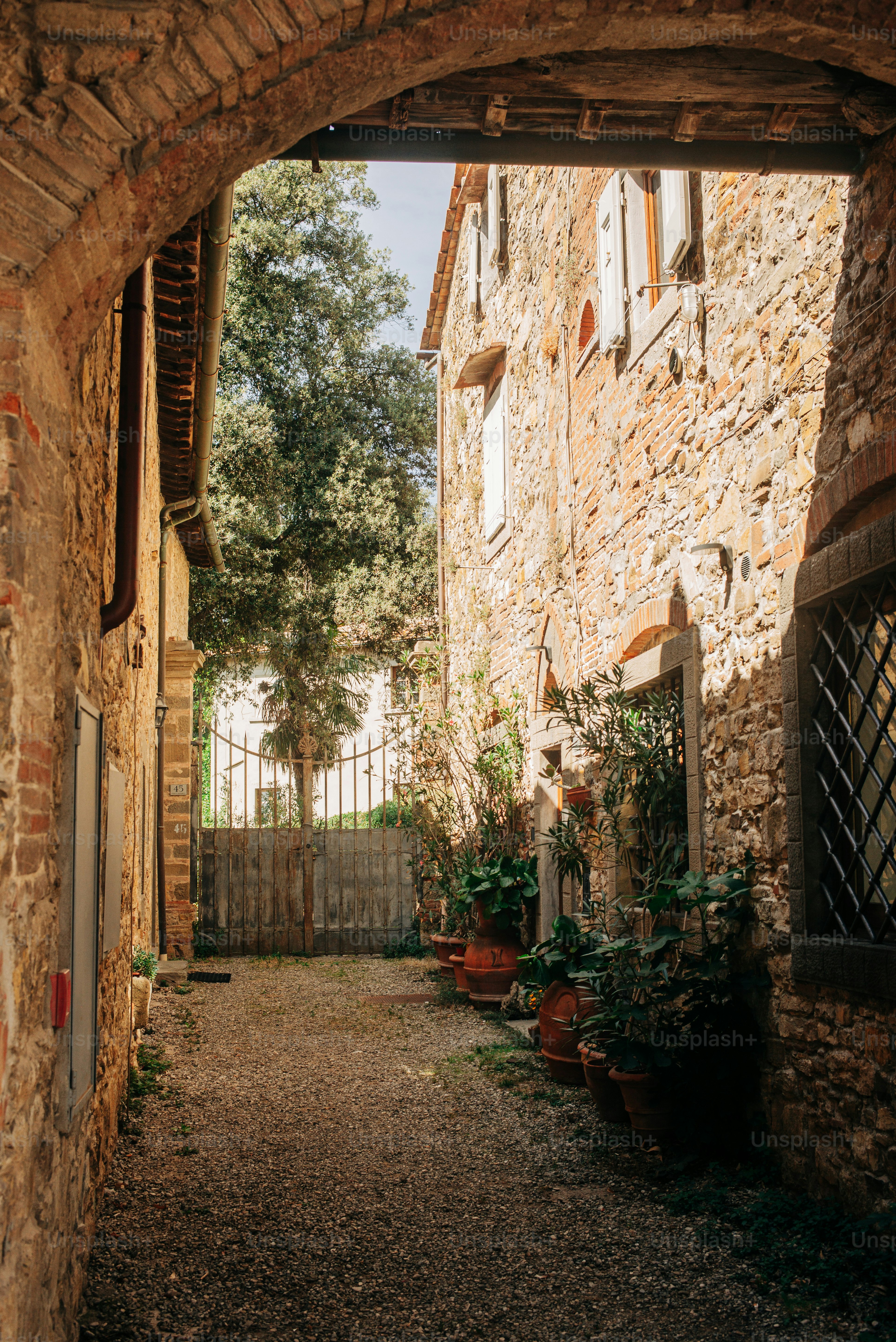 Stone buildings and potted plants in a tuscan alley.
