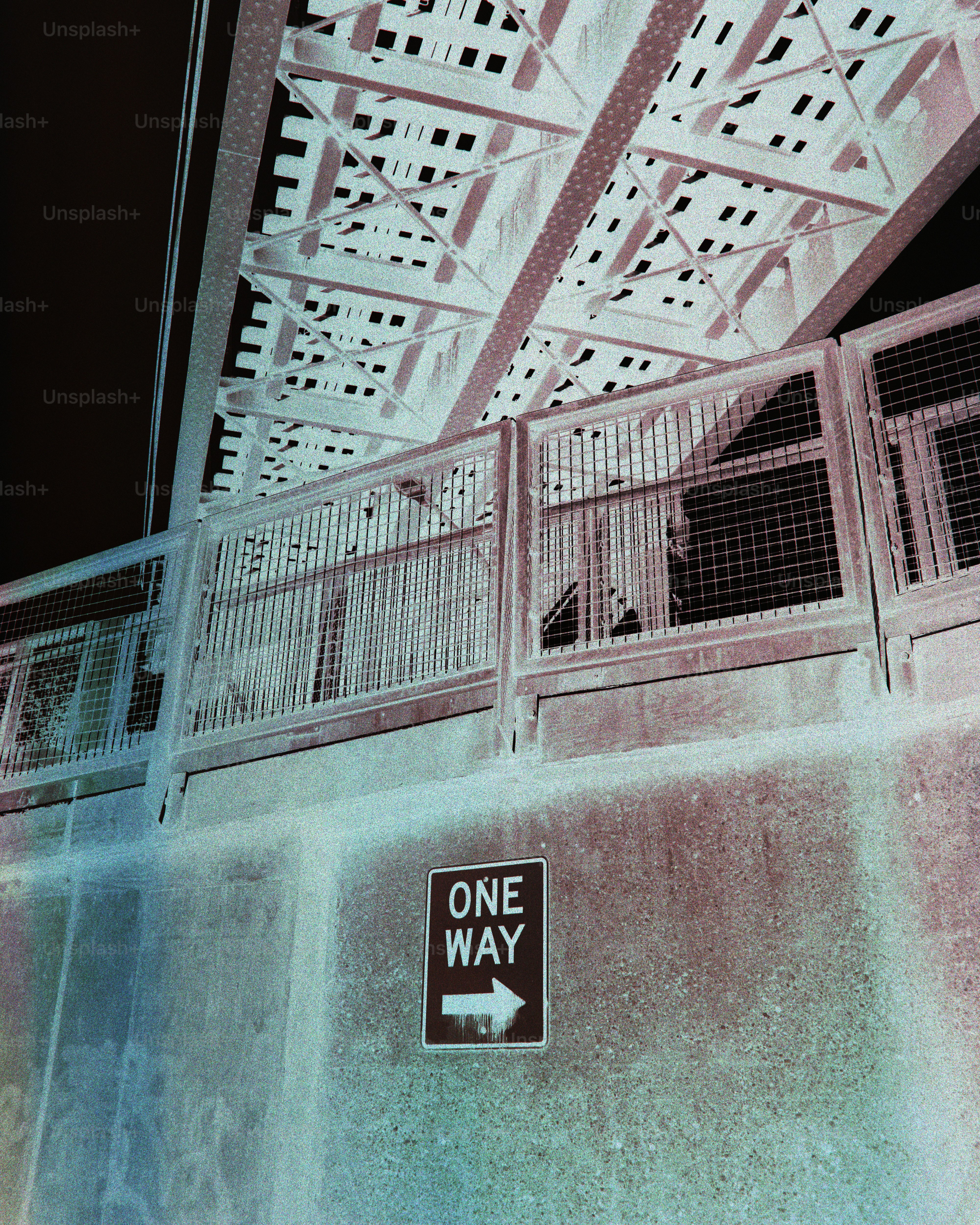 A one way sign under a bridge