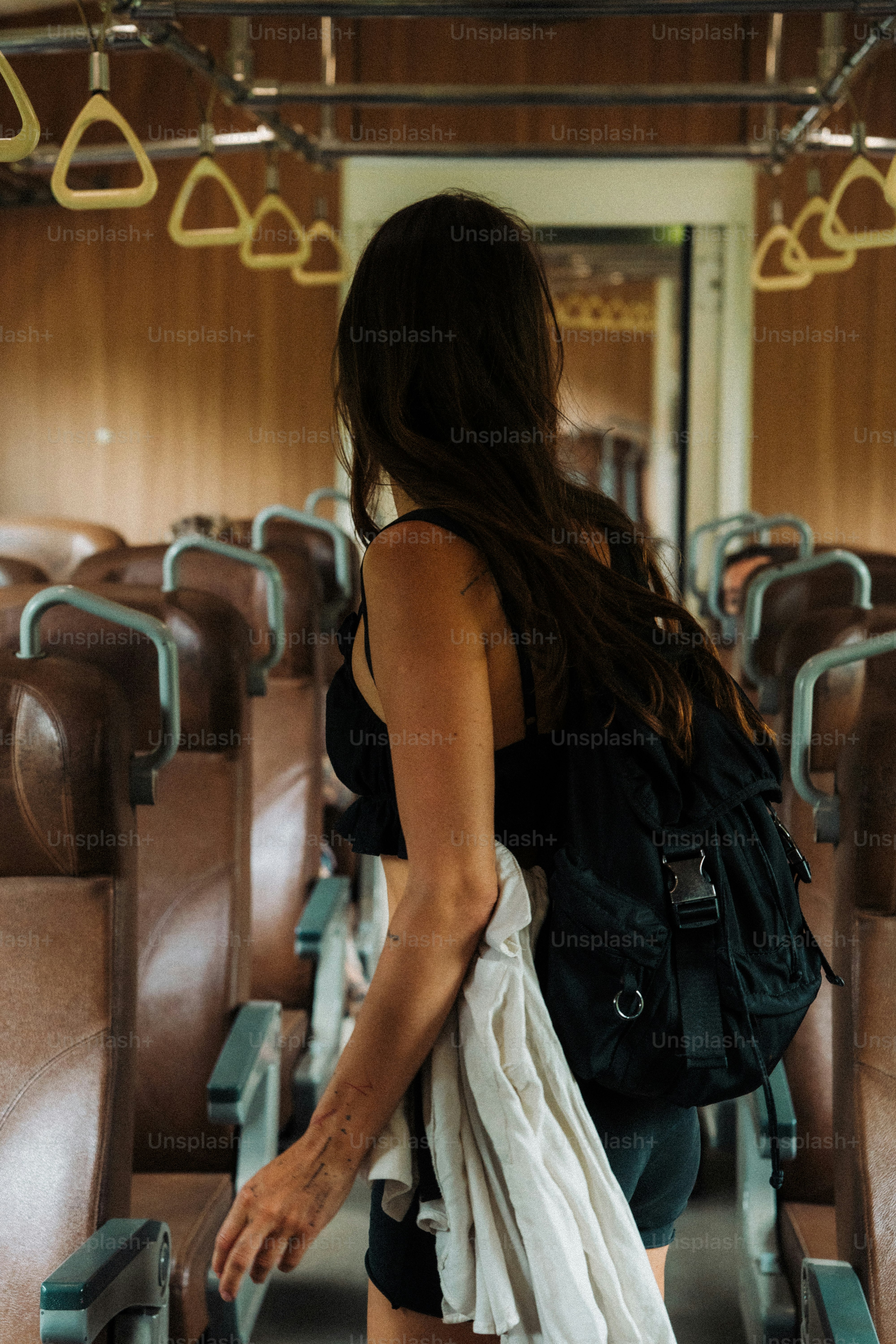 Woman with backpack walking through empty train car.