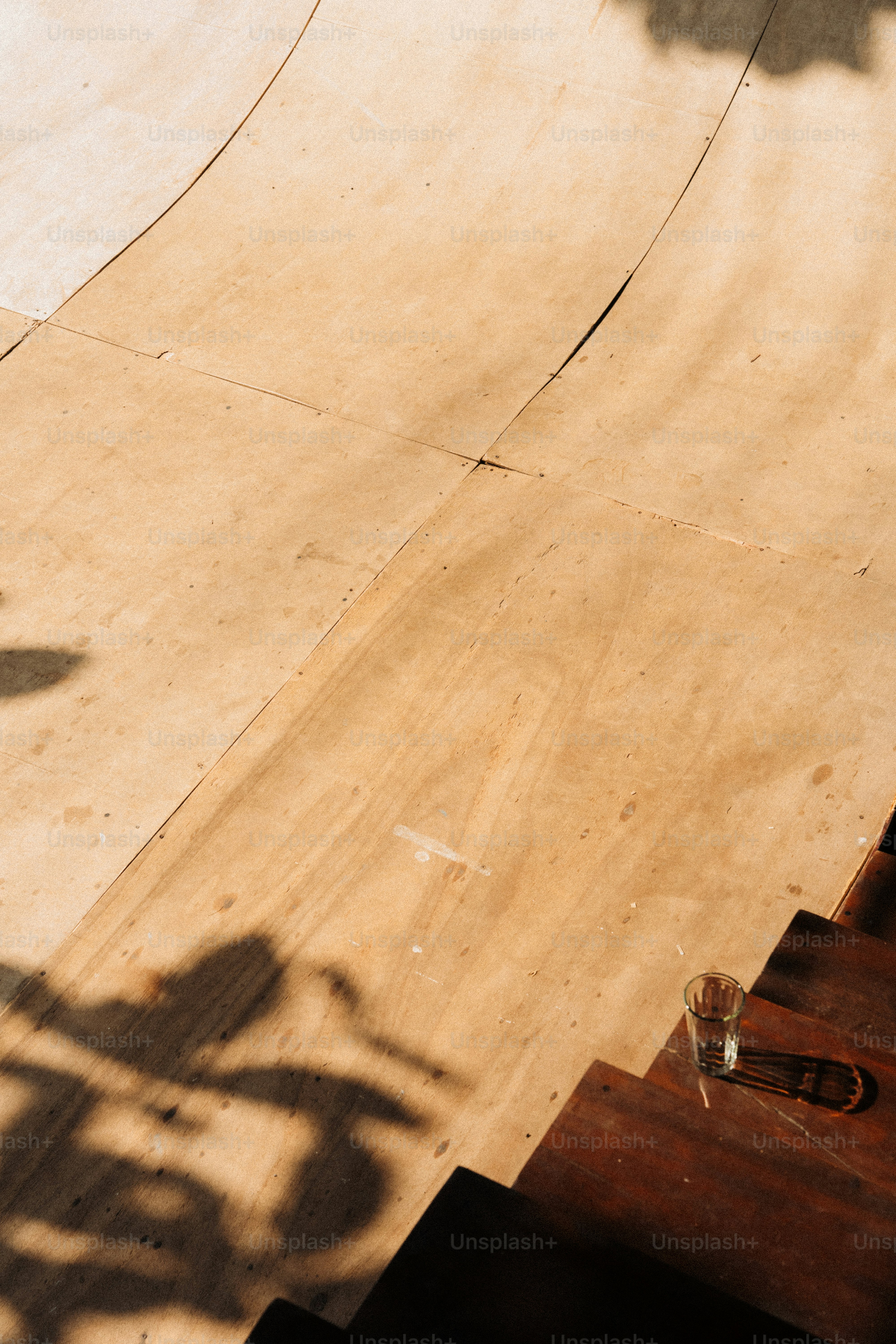 Wooden stairs leading to a curved ramp with shadows.
