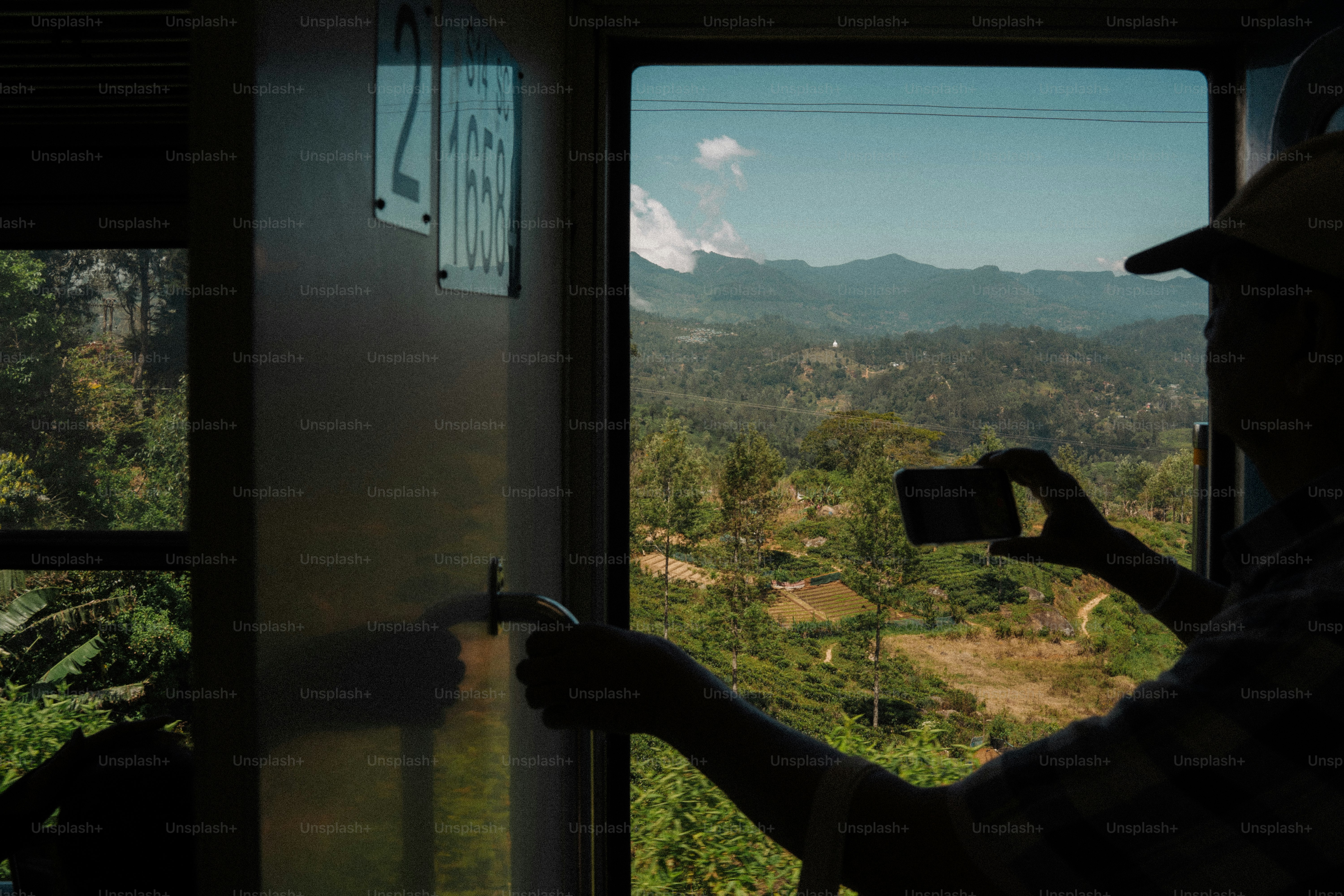 Person taking picture of mountain landscape from train window
