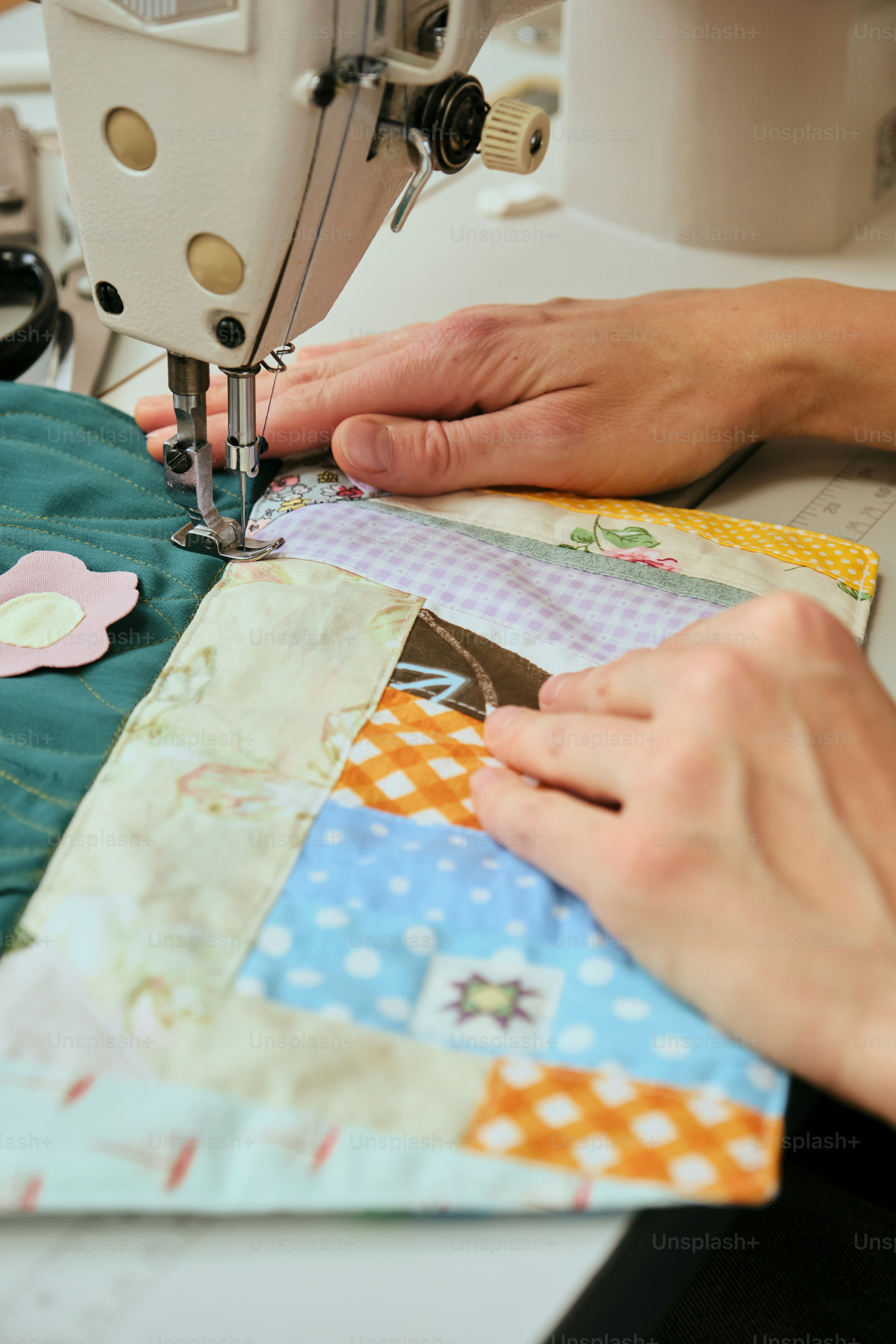 Mãos costurando uma colcha colorida de patchwork na máquina