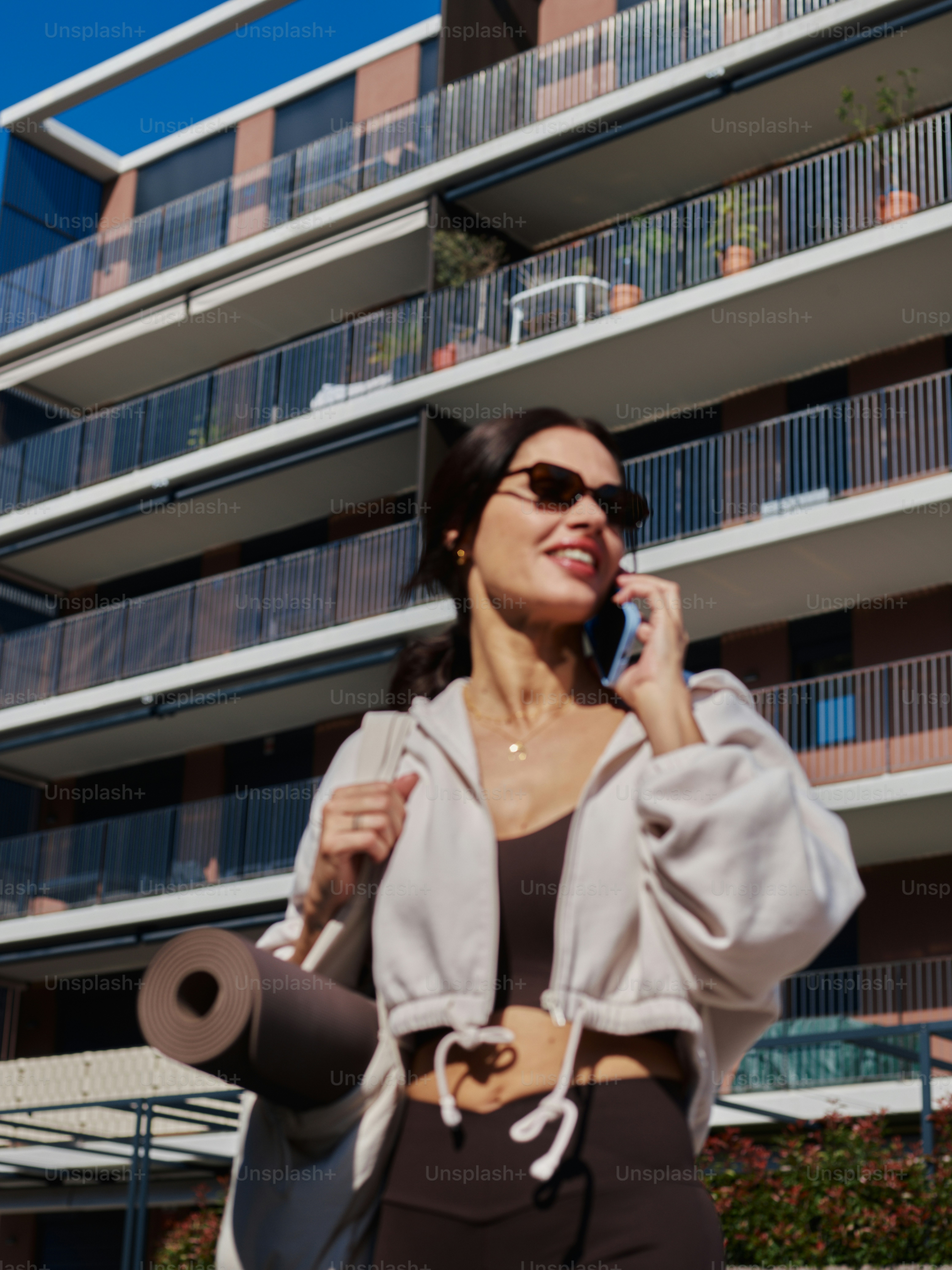 Woman adjusting sunglasses with building and sky - Photo on Unsplash+