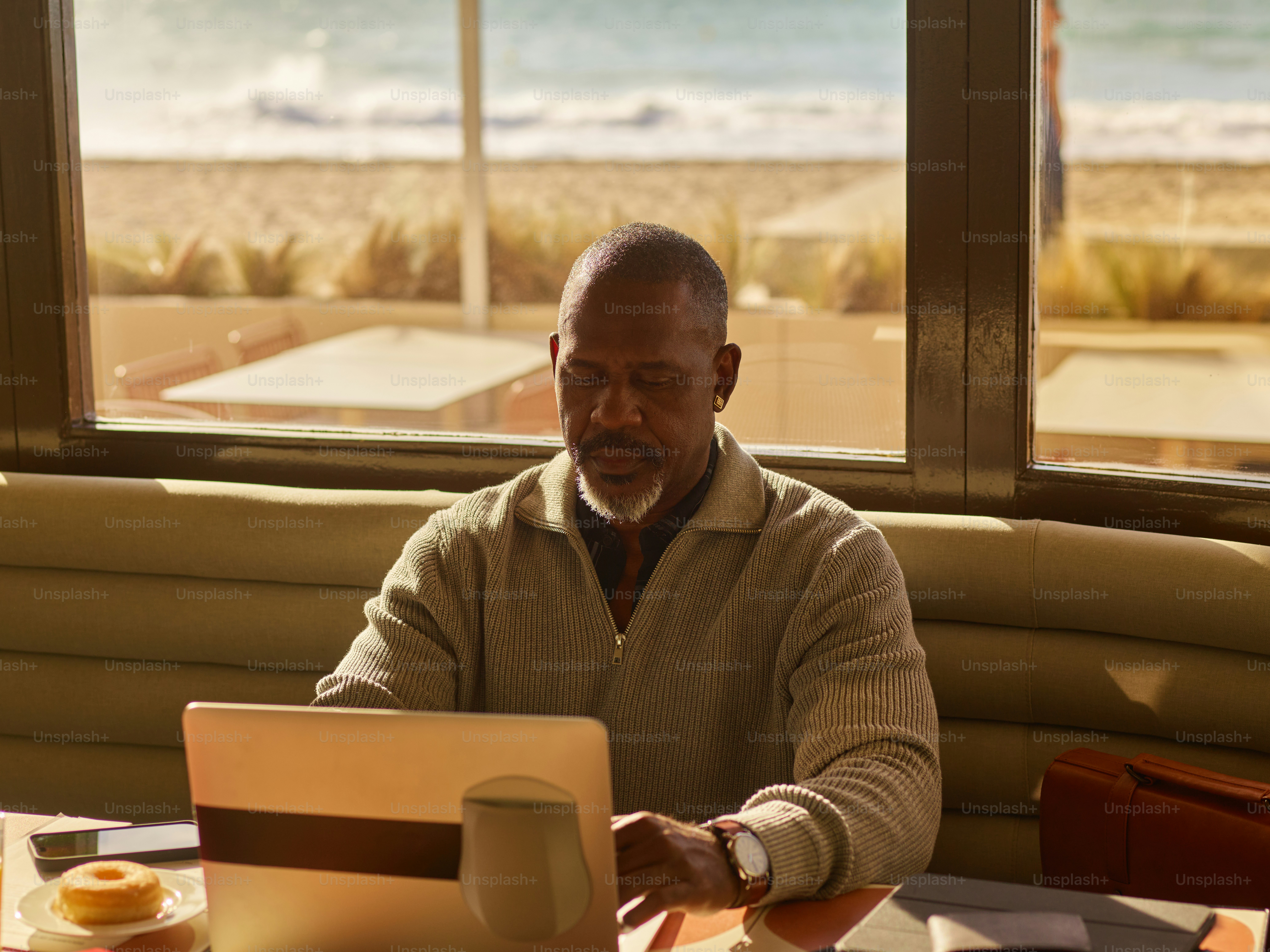 Man working on laptop with beach view