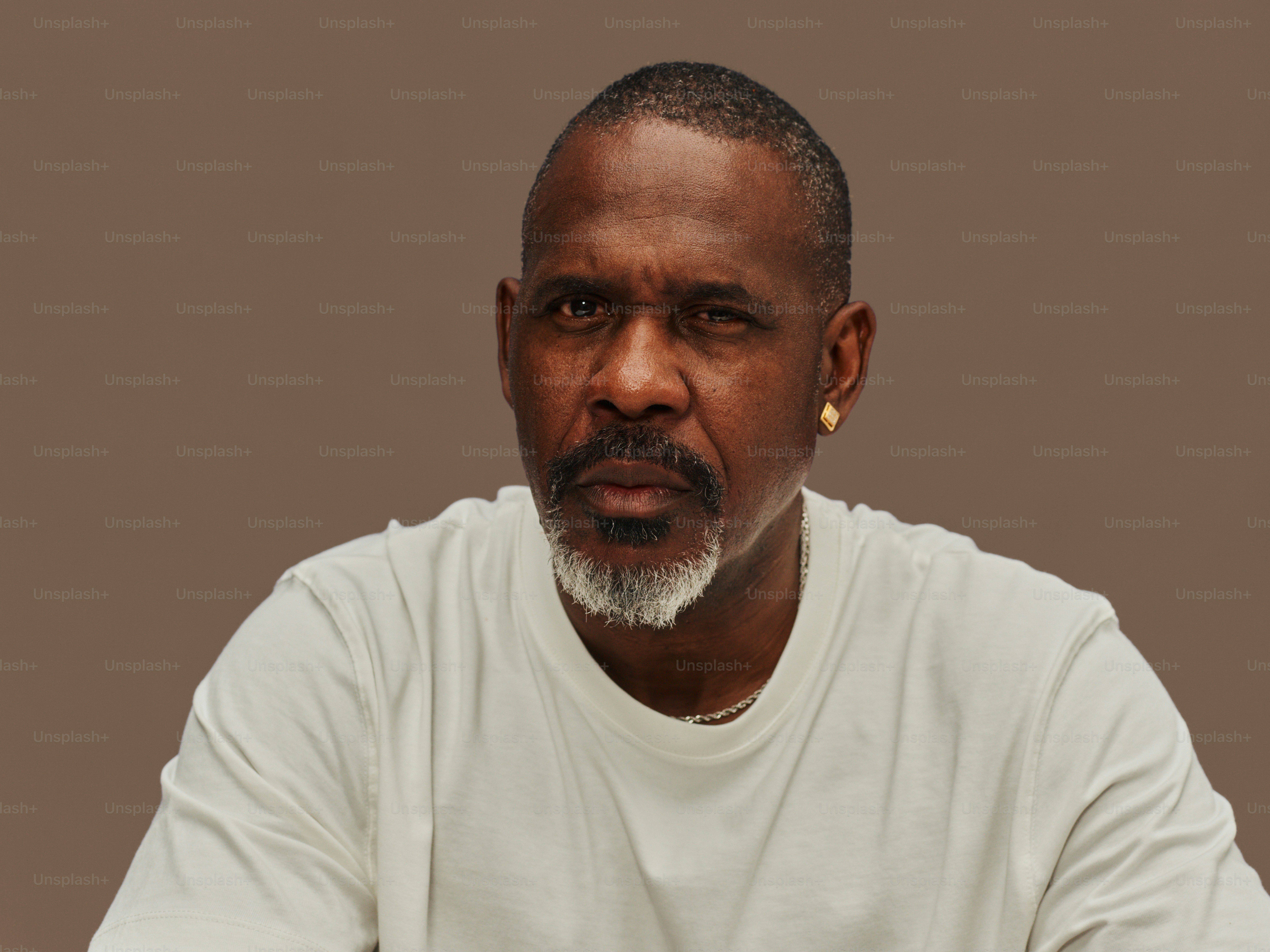 Man with beard and white t-shirt looking forward.