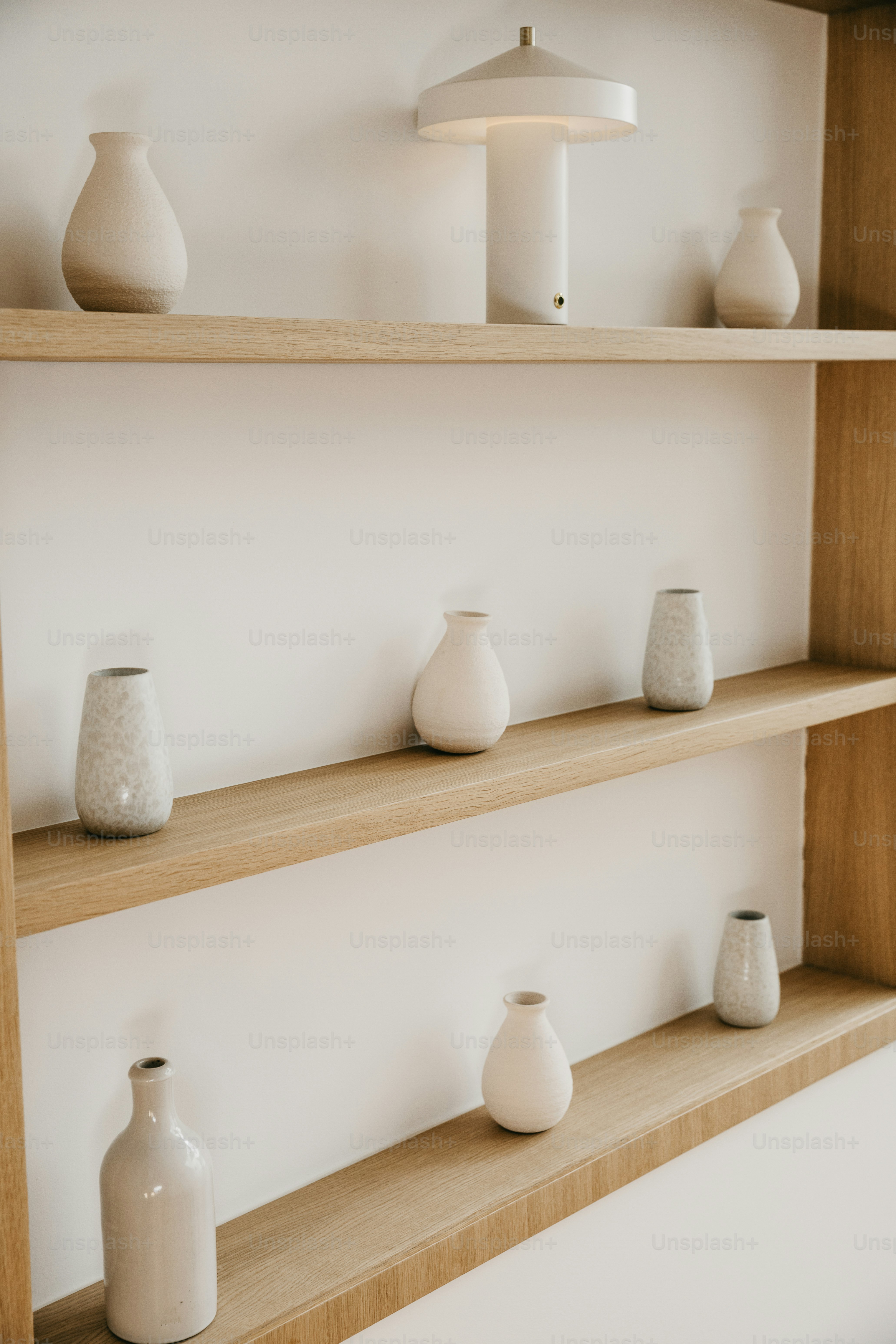 Various neutral-toned vases displayed on wooden shelves.