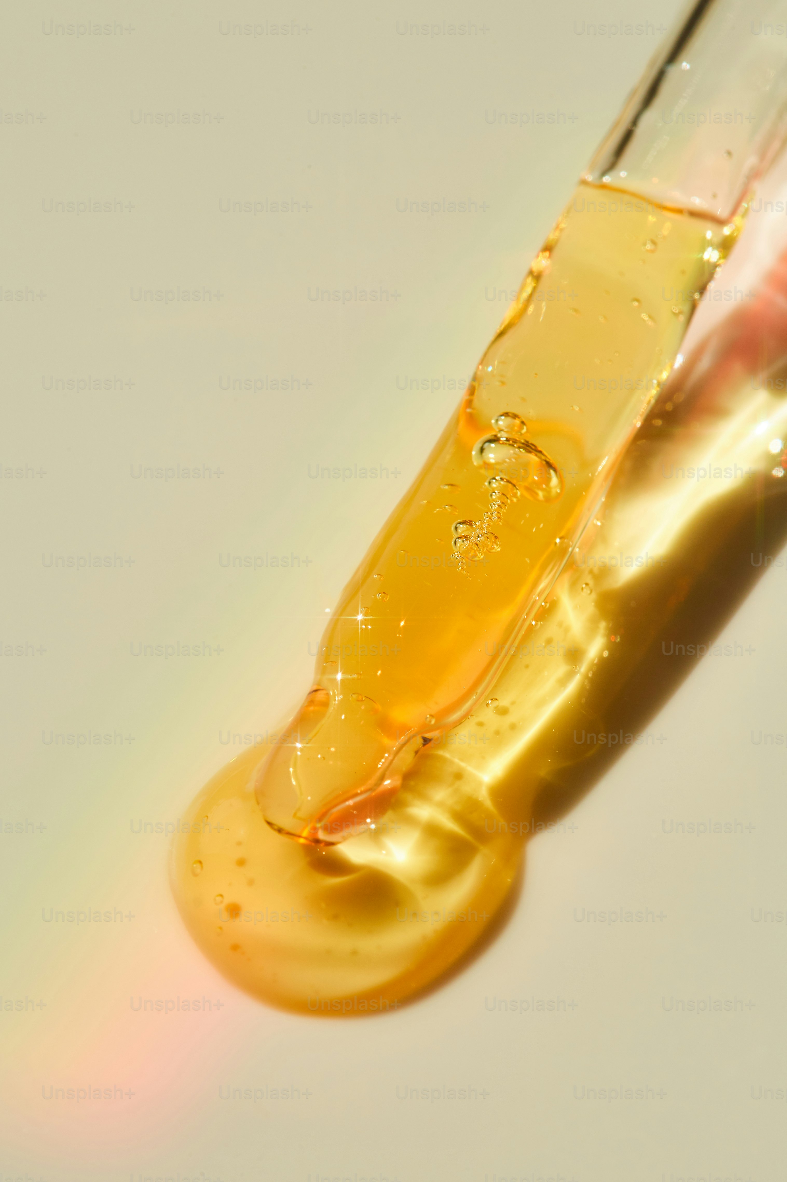 Goldenes Serum, das von einer Glaspipette tropft.