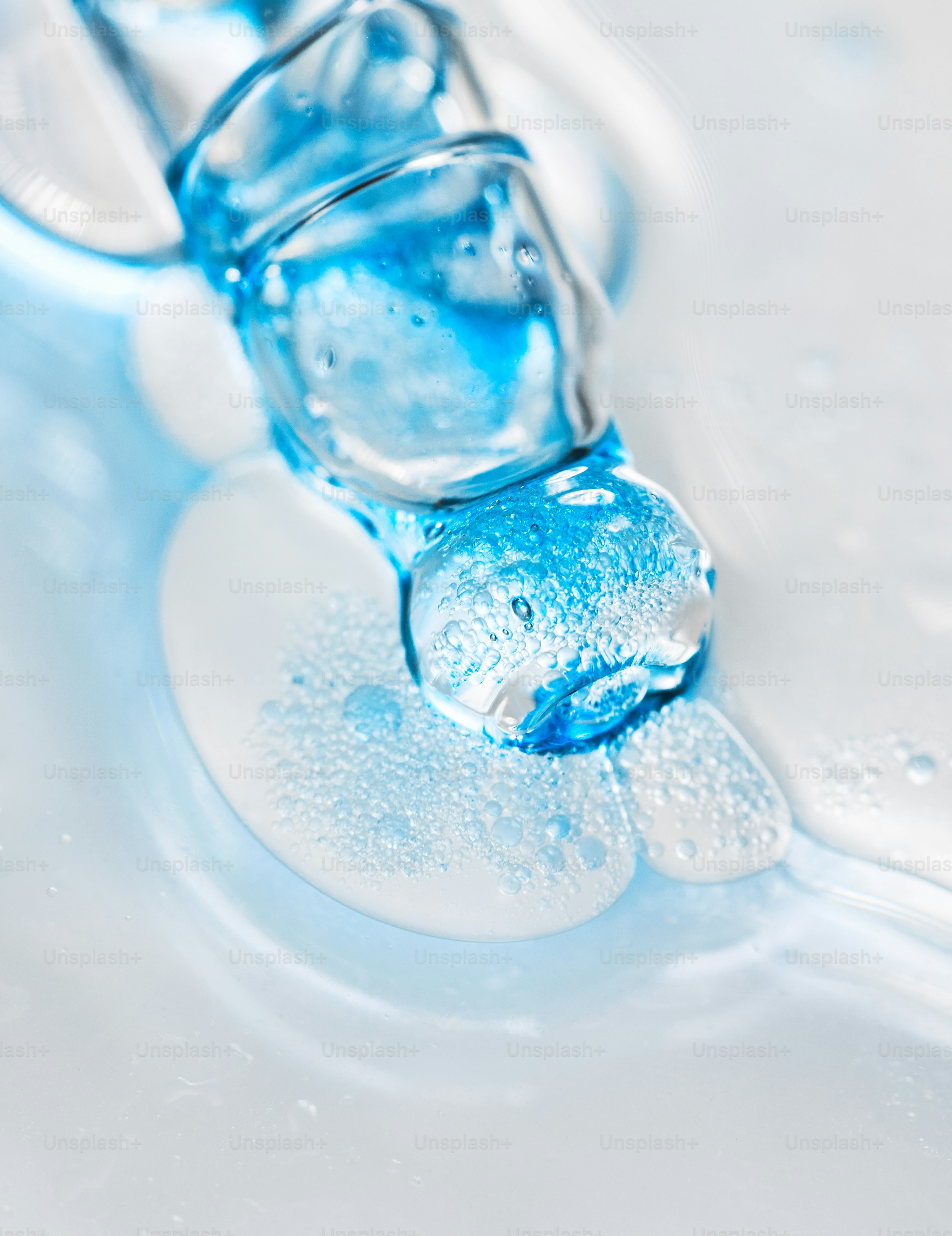 A dropper dispensing blue liquid onto a white surface photo – Texture ...