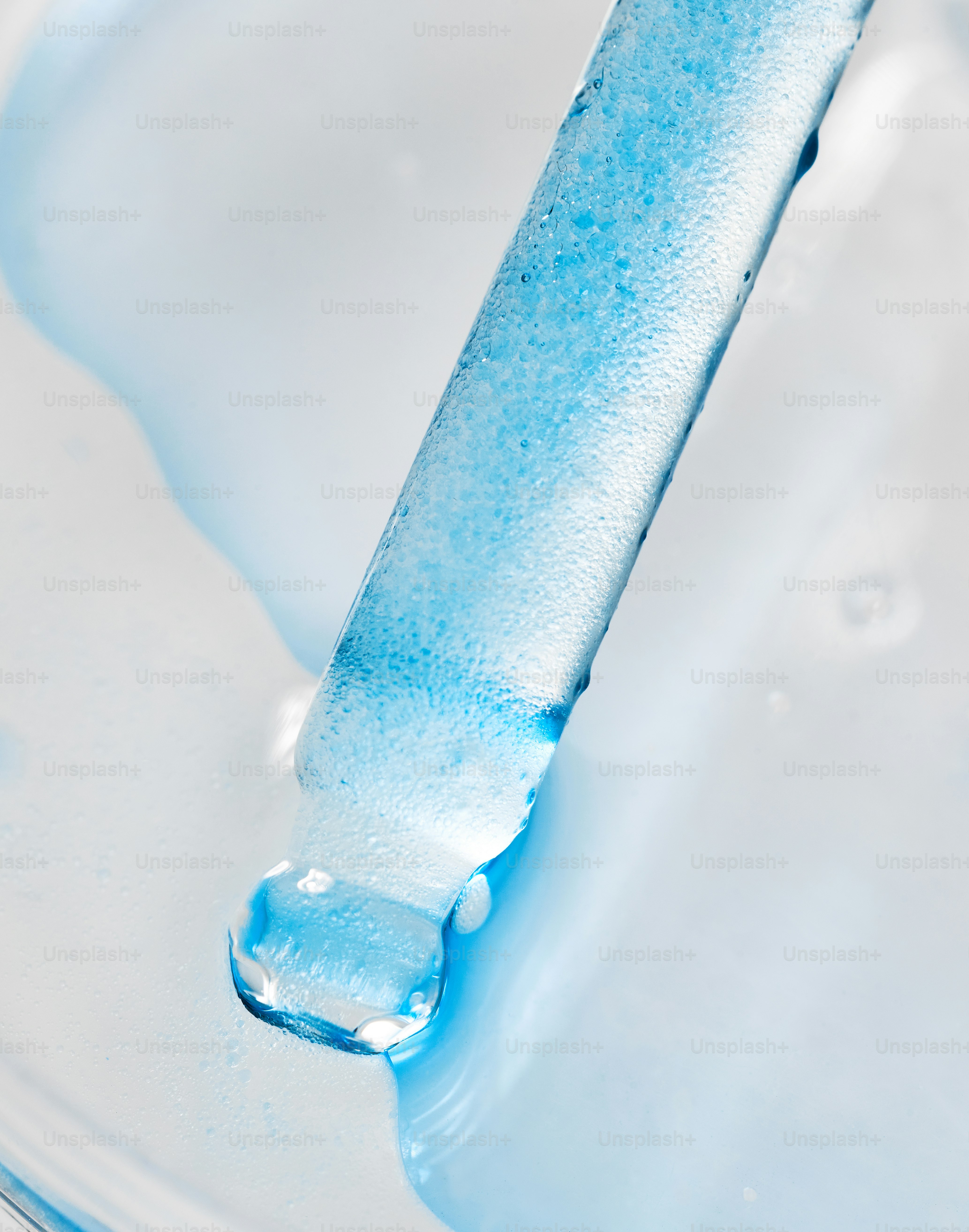 A blue liquid drips from a glass dropper. photo – Texture Image on Unsplash