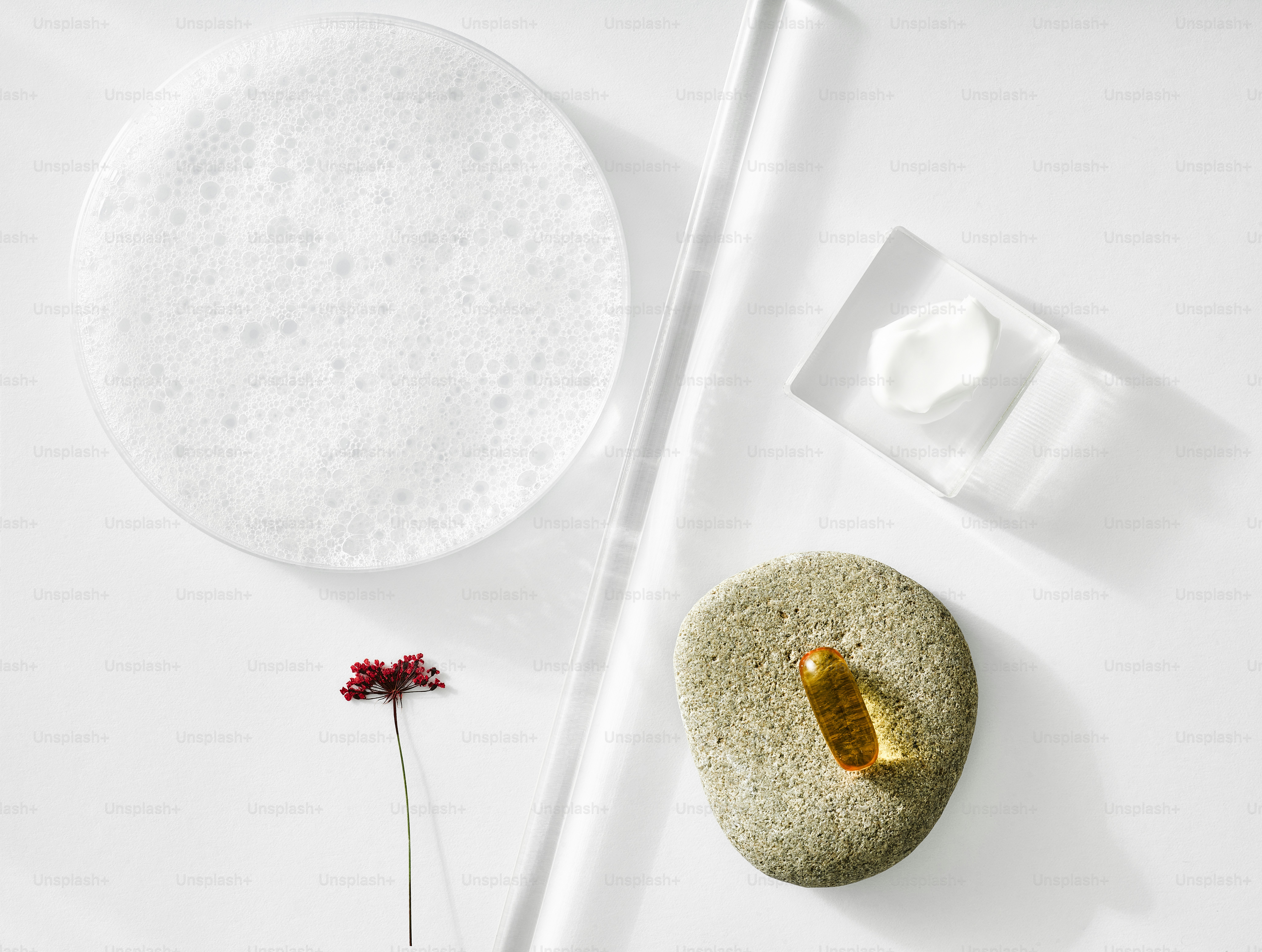 Foam, stone, and cosmetic product on white background.