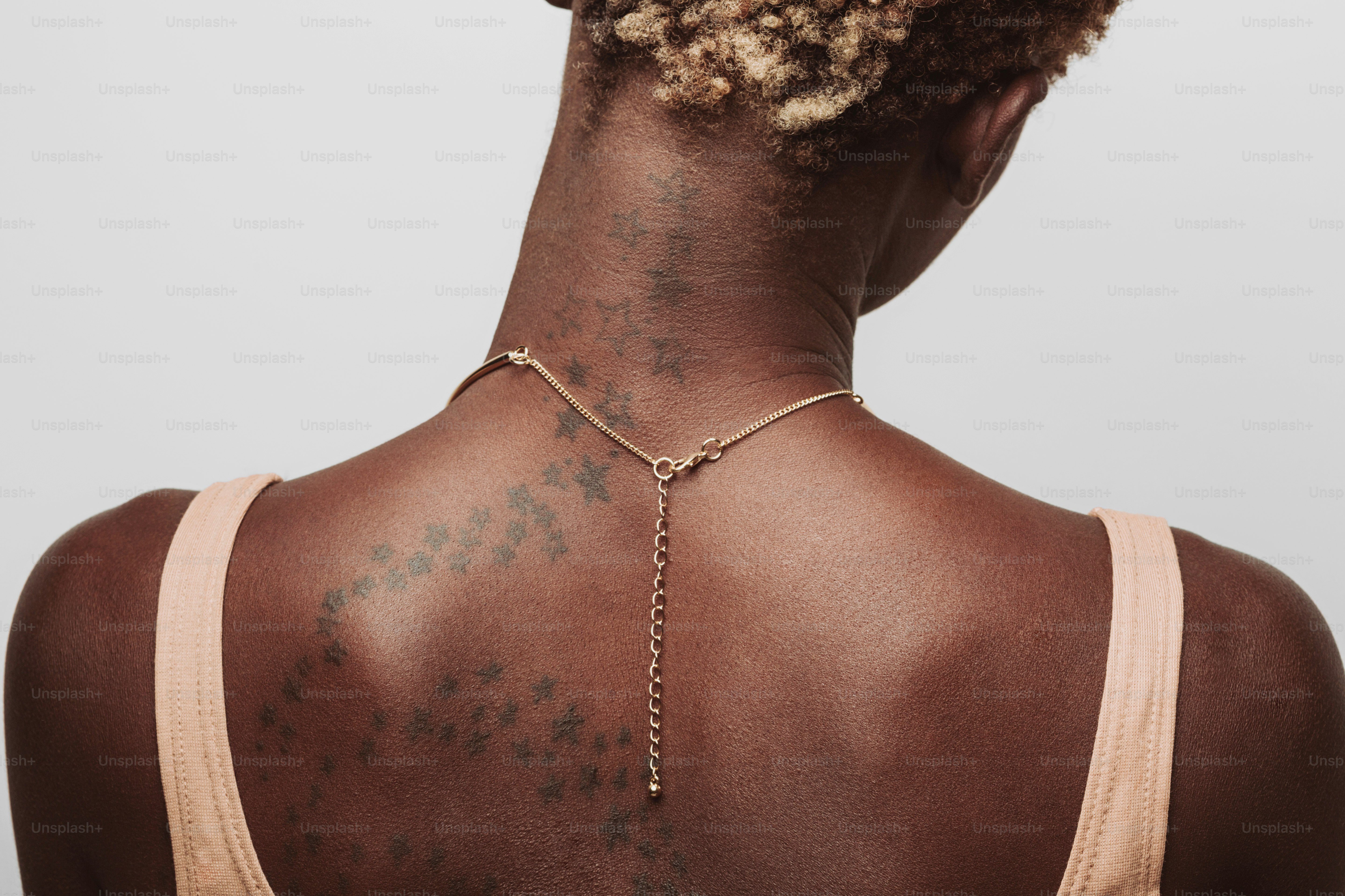 Woman with a gold necklace and tattoos on back