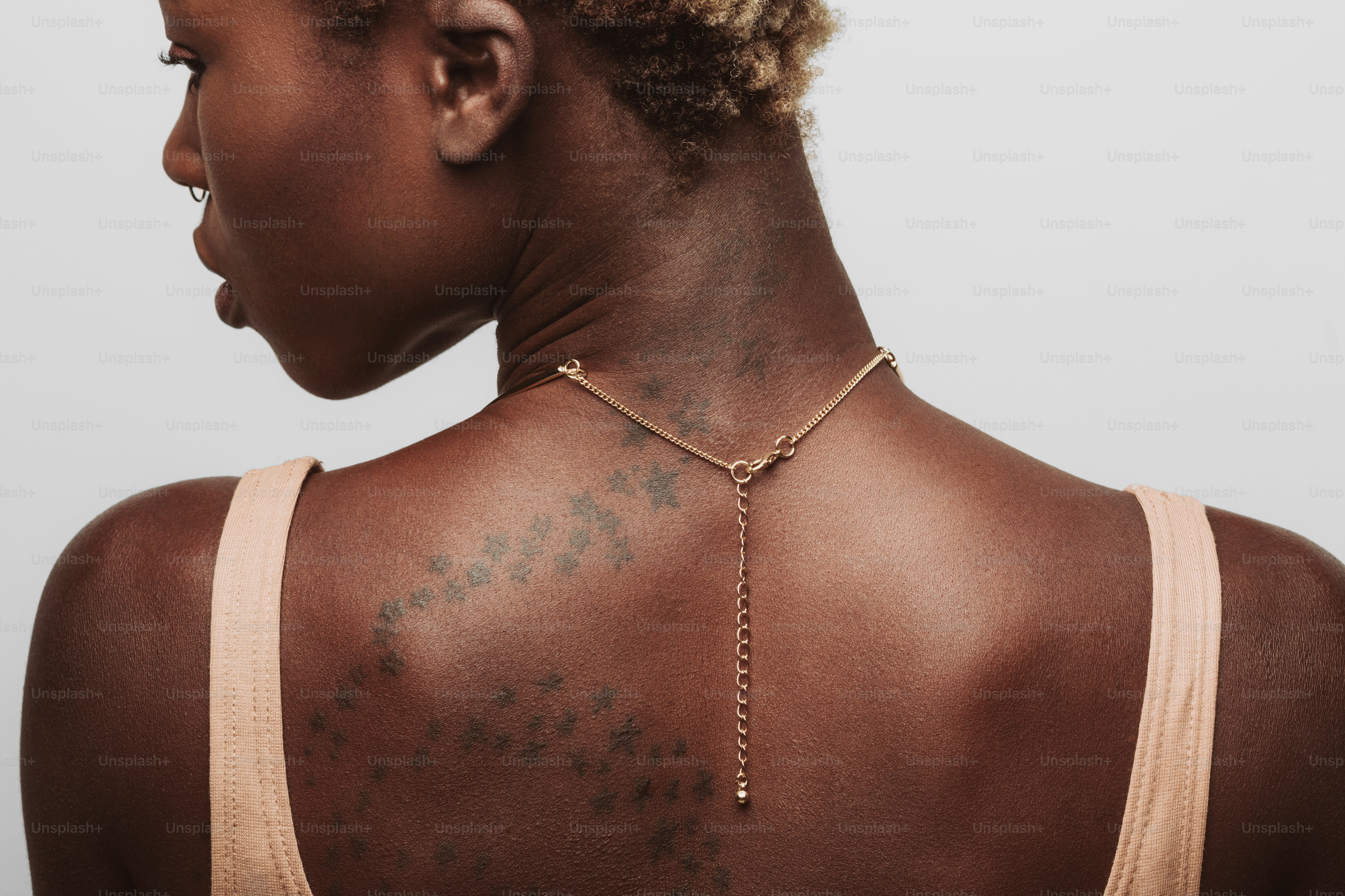 Woman wearing a delicate gold necklace on her back