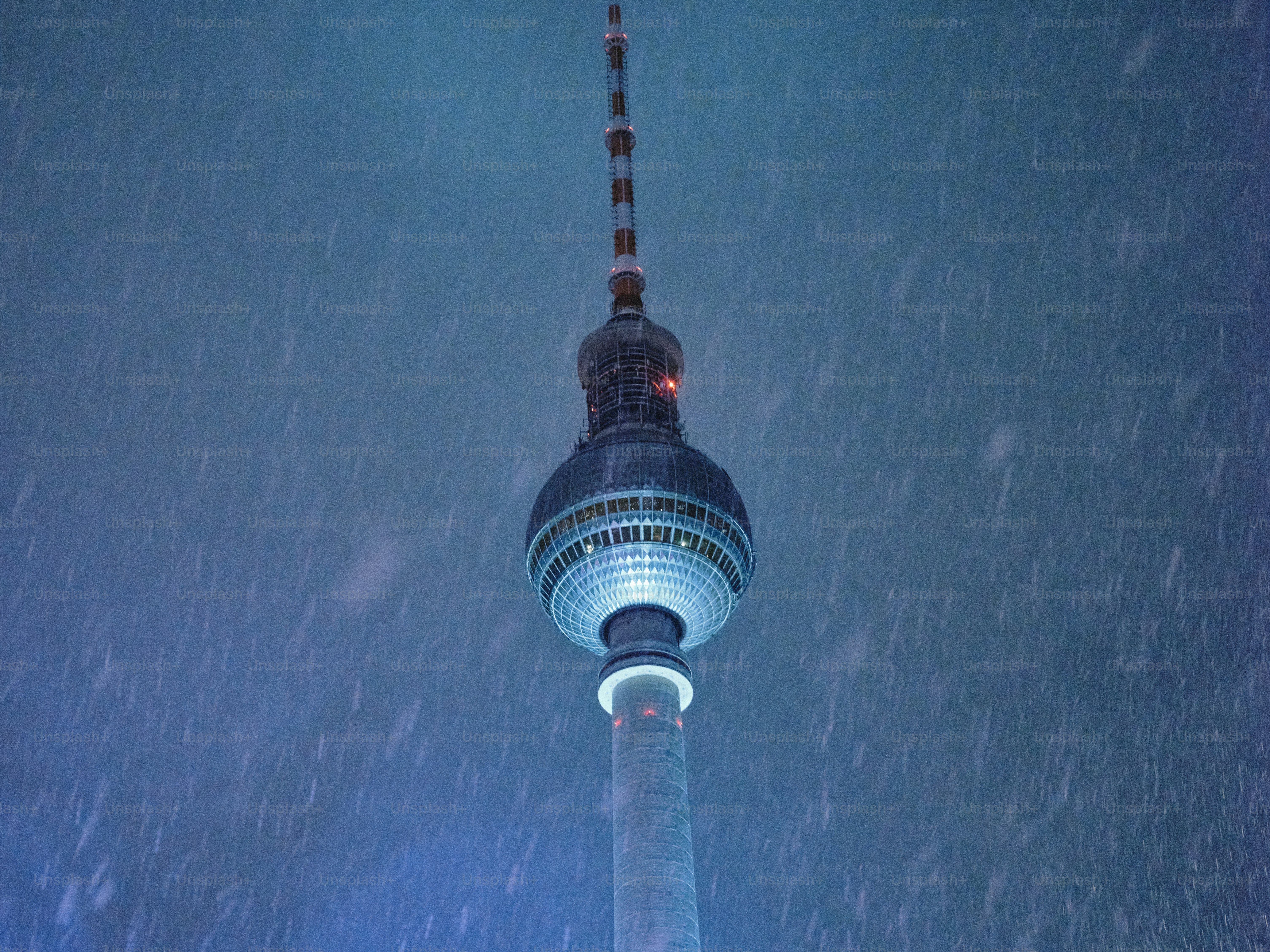 Television tower at night during snowfall