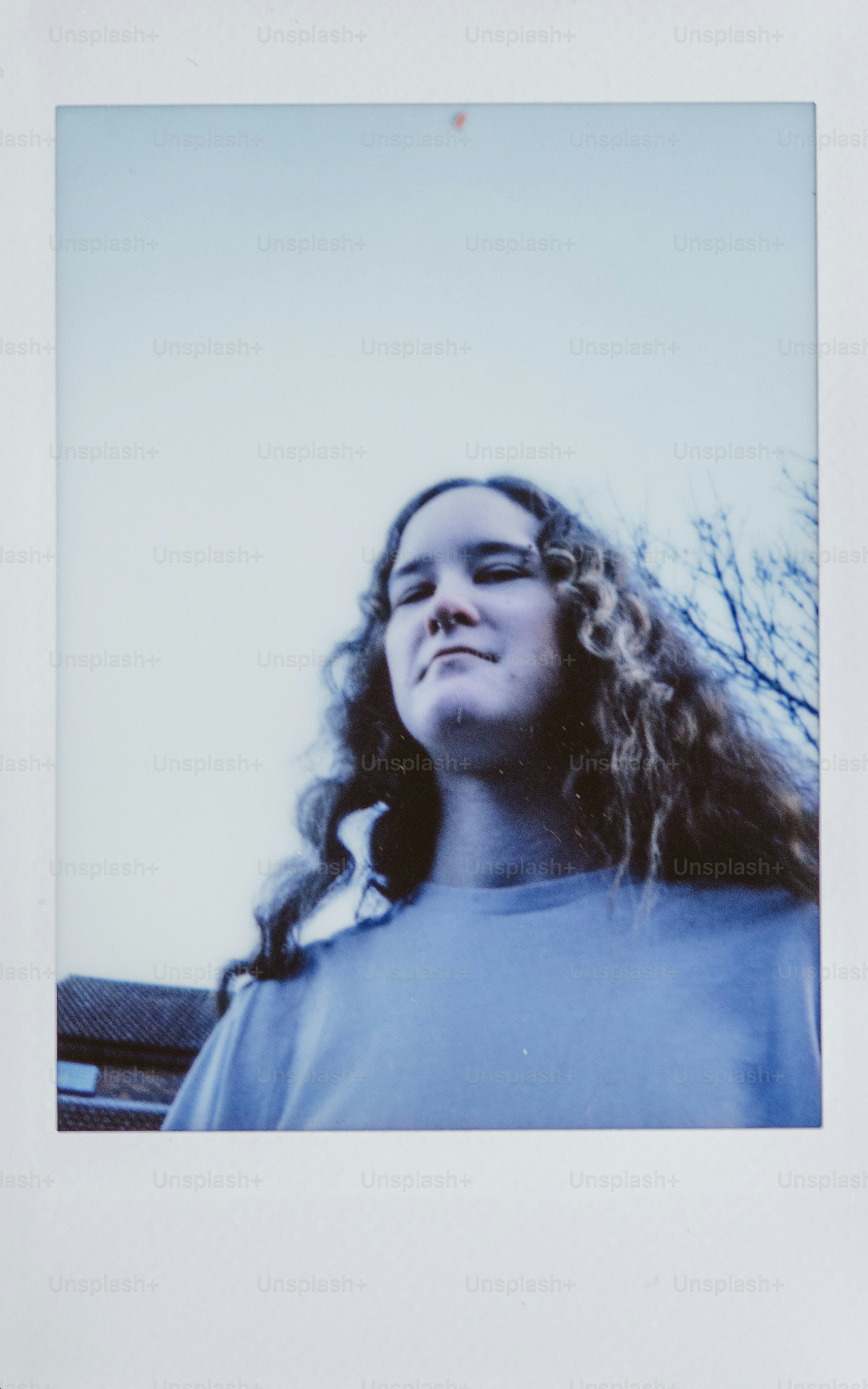 A young woman with curly hair looks upwards.
