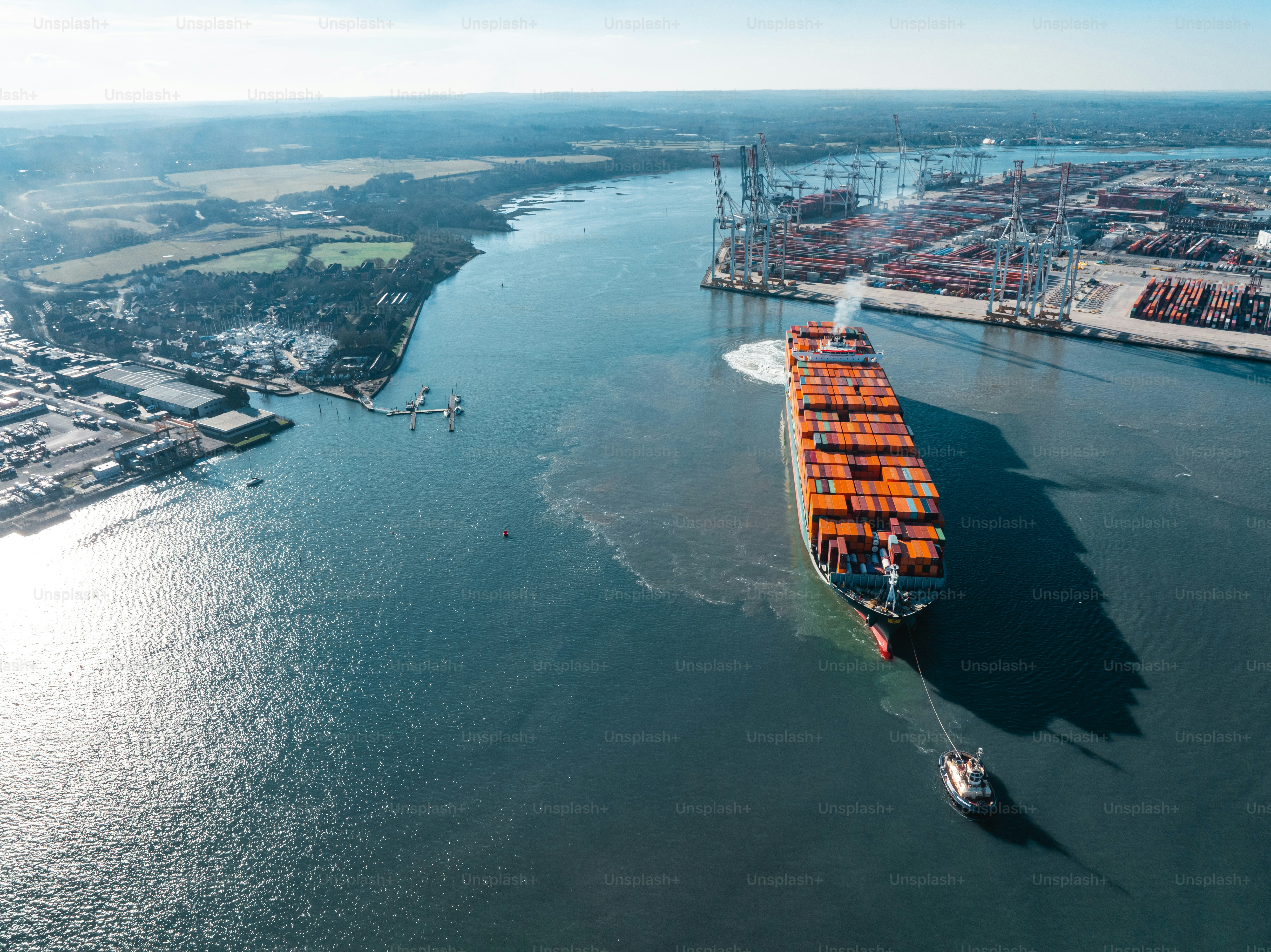 Luftaufnahme eines Schleppers, der ein Containerschiff in Southampton, Großbritannien, schleppt
