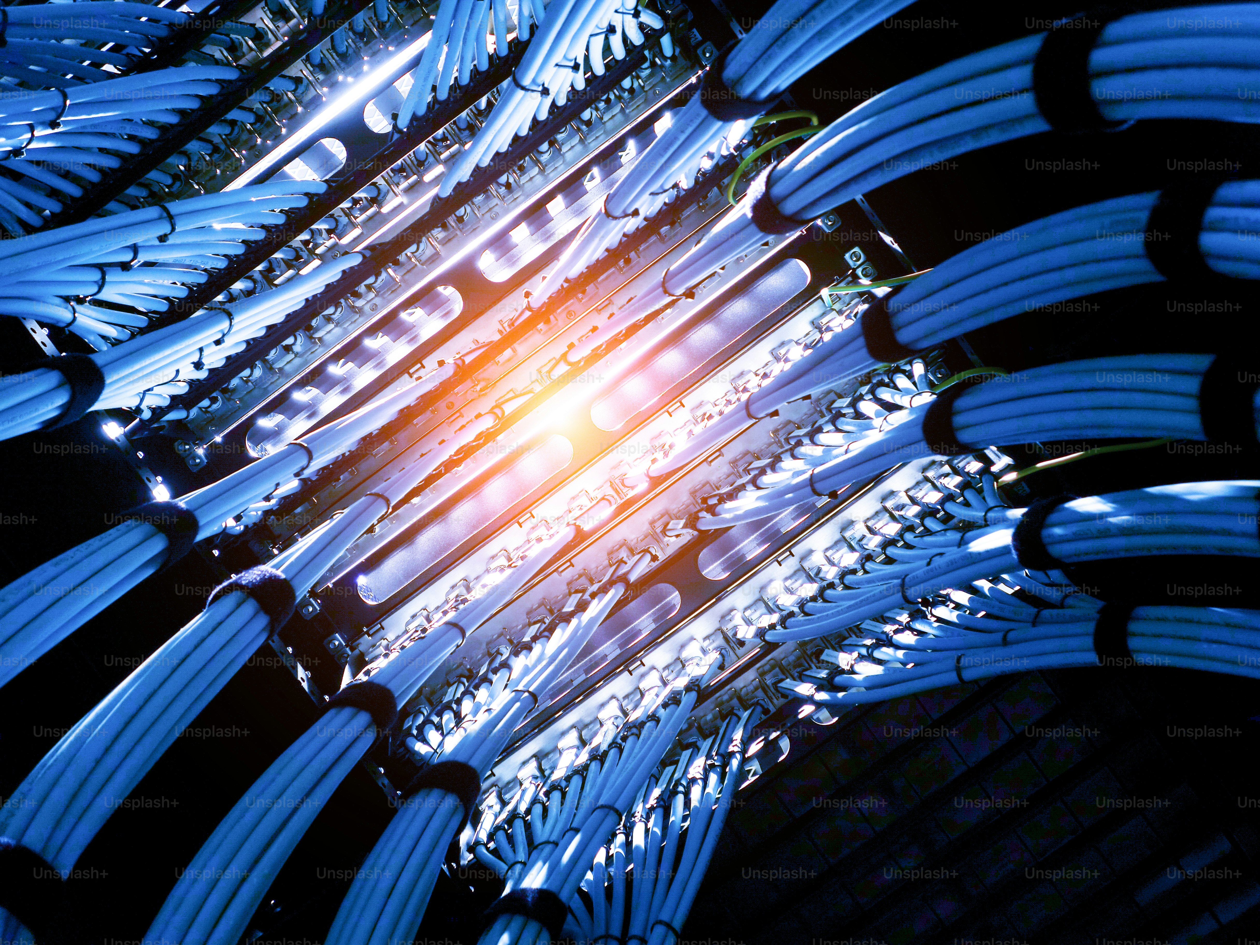 Una vista cautivadora de cables de fibra óptica azules iluminados en un centro de datos, mostrando infraestructuras tecnológicas modernas y sistemas de comunicación eficientes.