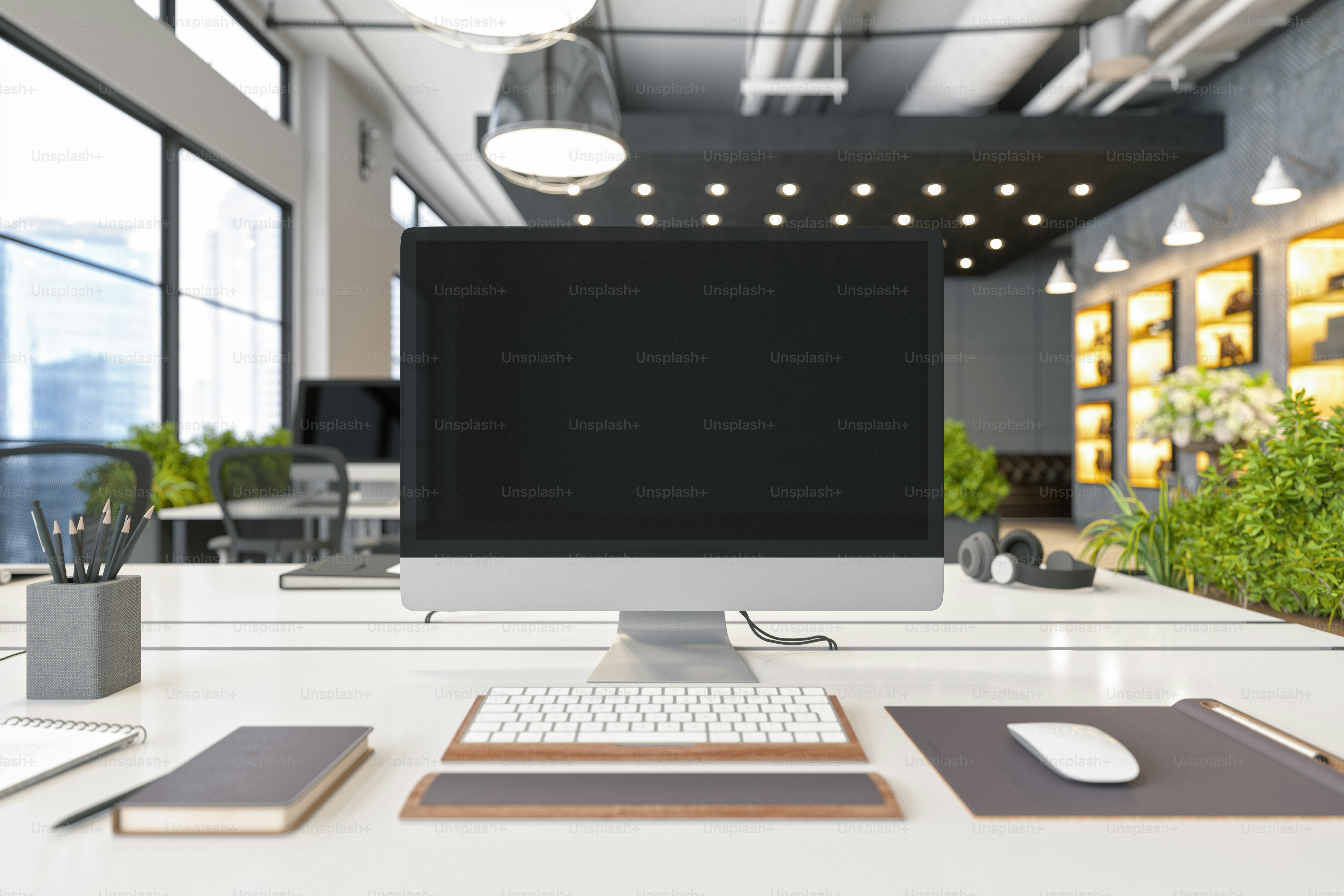 Blank computer screen on modern office desk in a sustainable green co ...