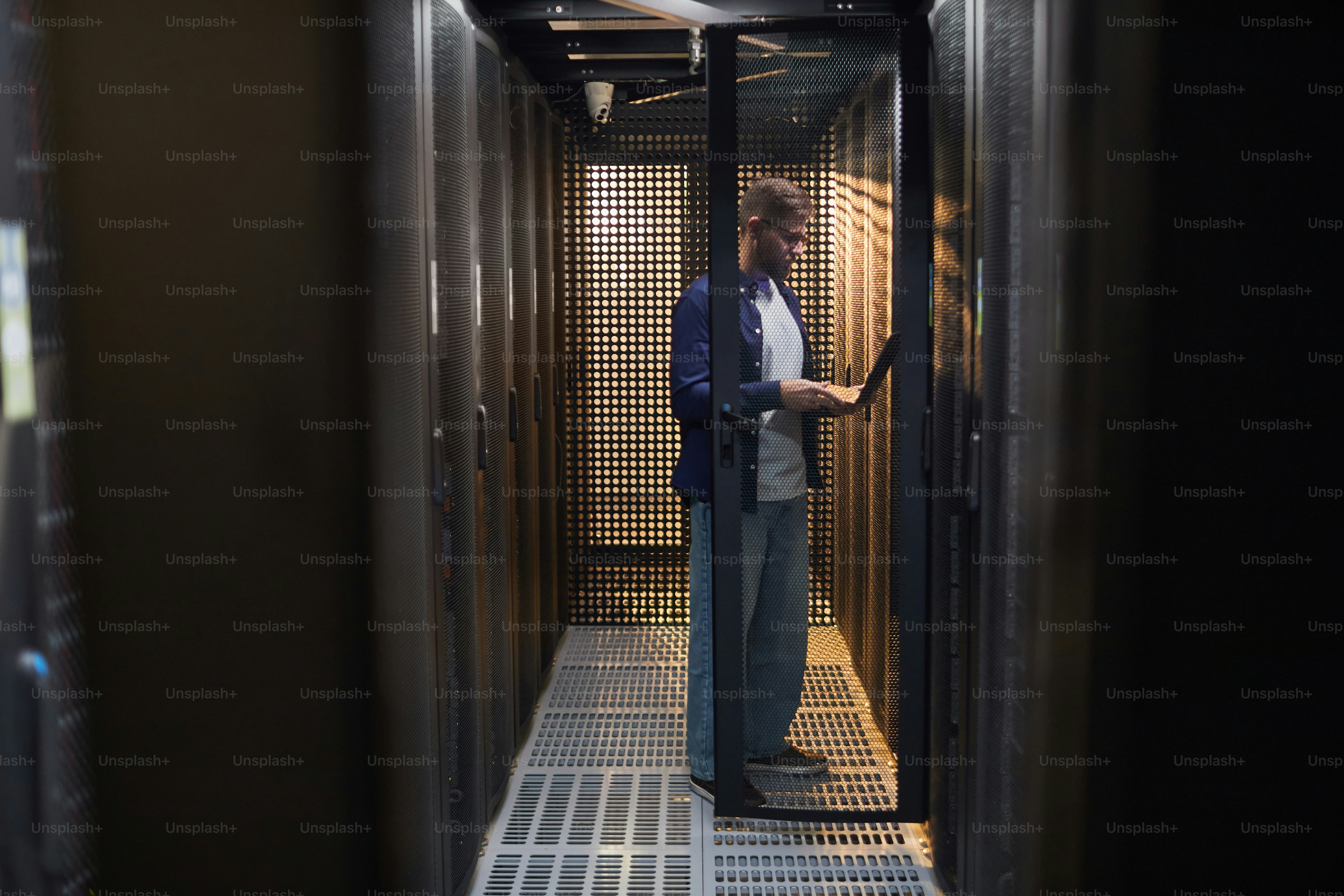 Technician performing routine maintenance in server room with various ...