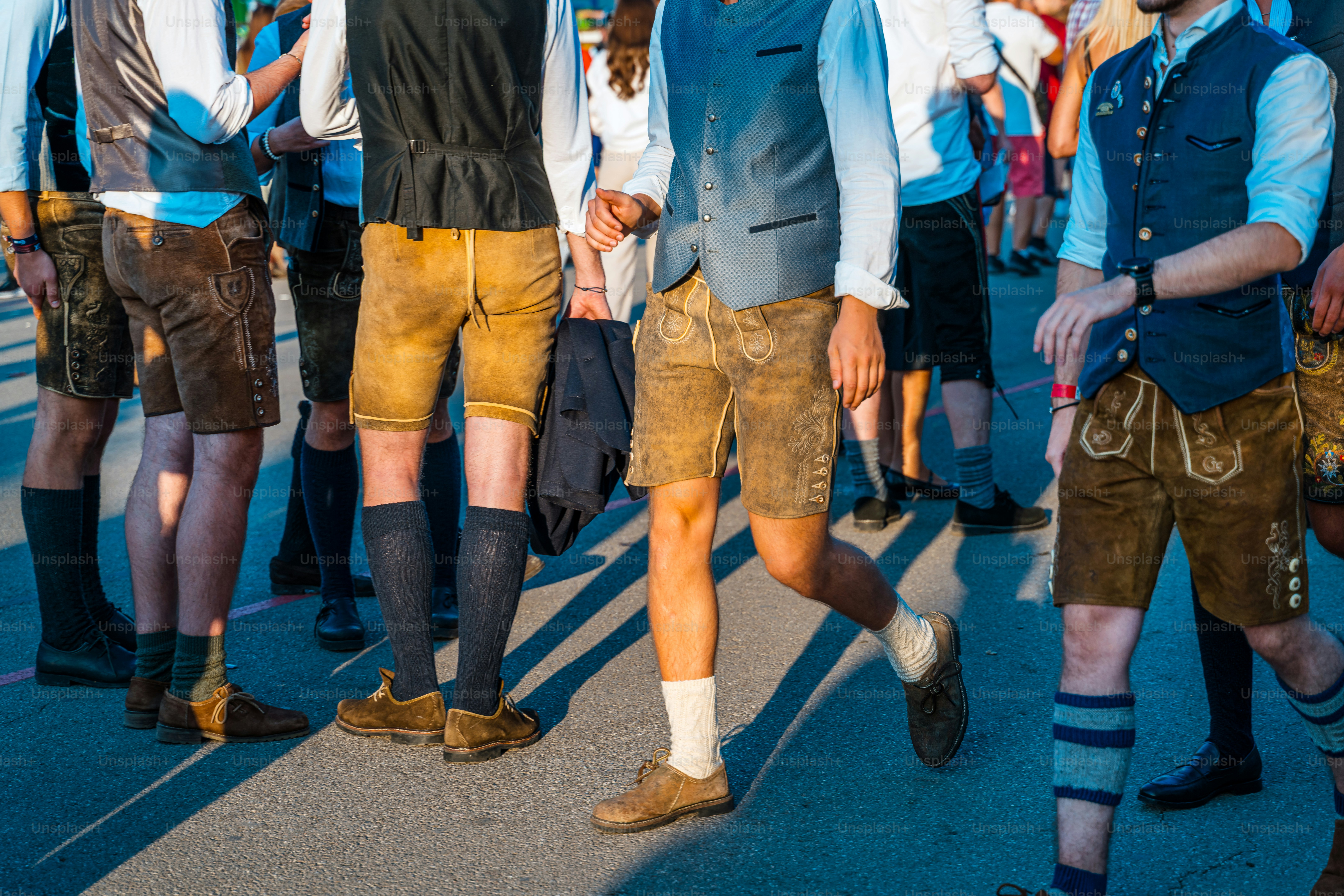 Vibrant crowd scene from Munich’s Volksfest showing men in lederhosen and traditional vests, enjoying festive outdoor atmosphere and social camaraderie at a world-renowned beer festival.