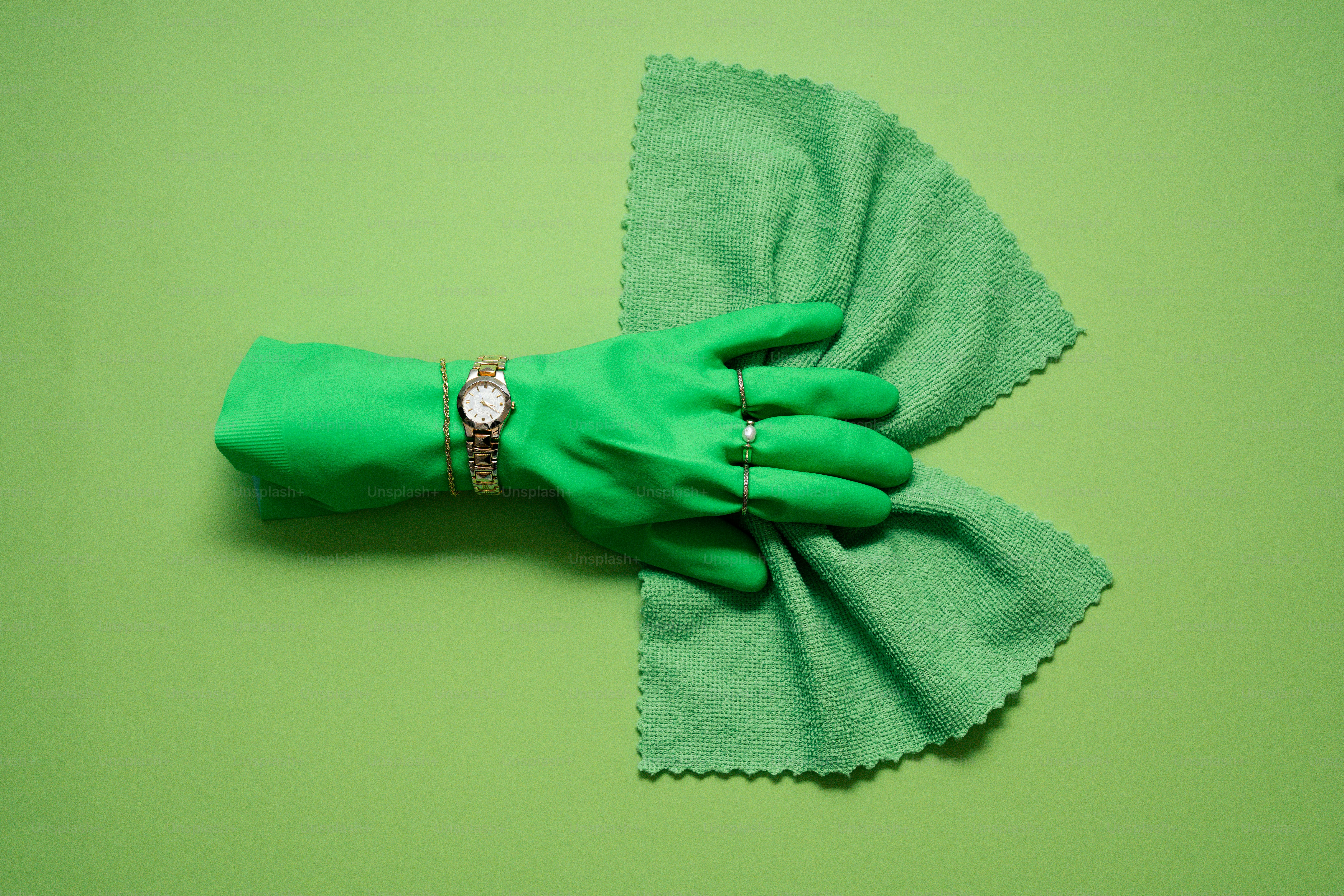 Green glove holding green cloth on green background