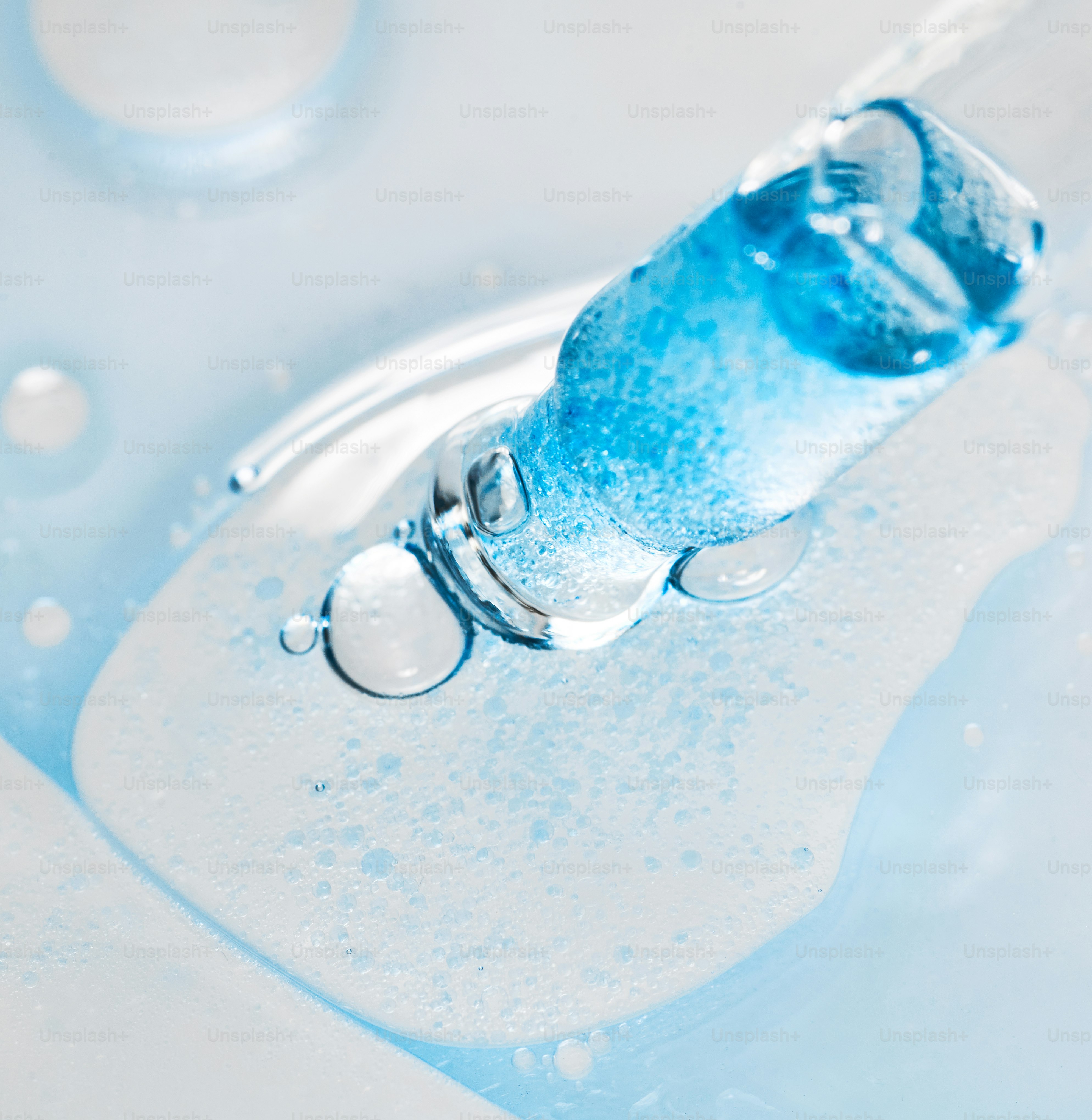 Blaue Flüssigkeit, die aus dem Glastropfen auf die Oberfläche tropft