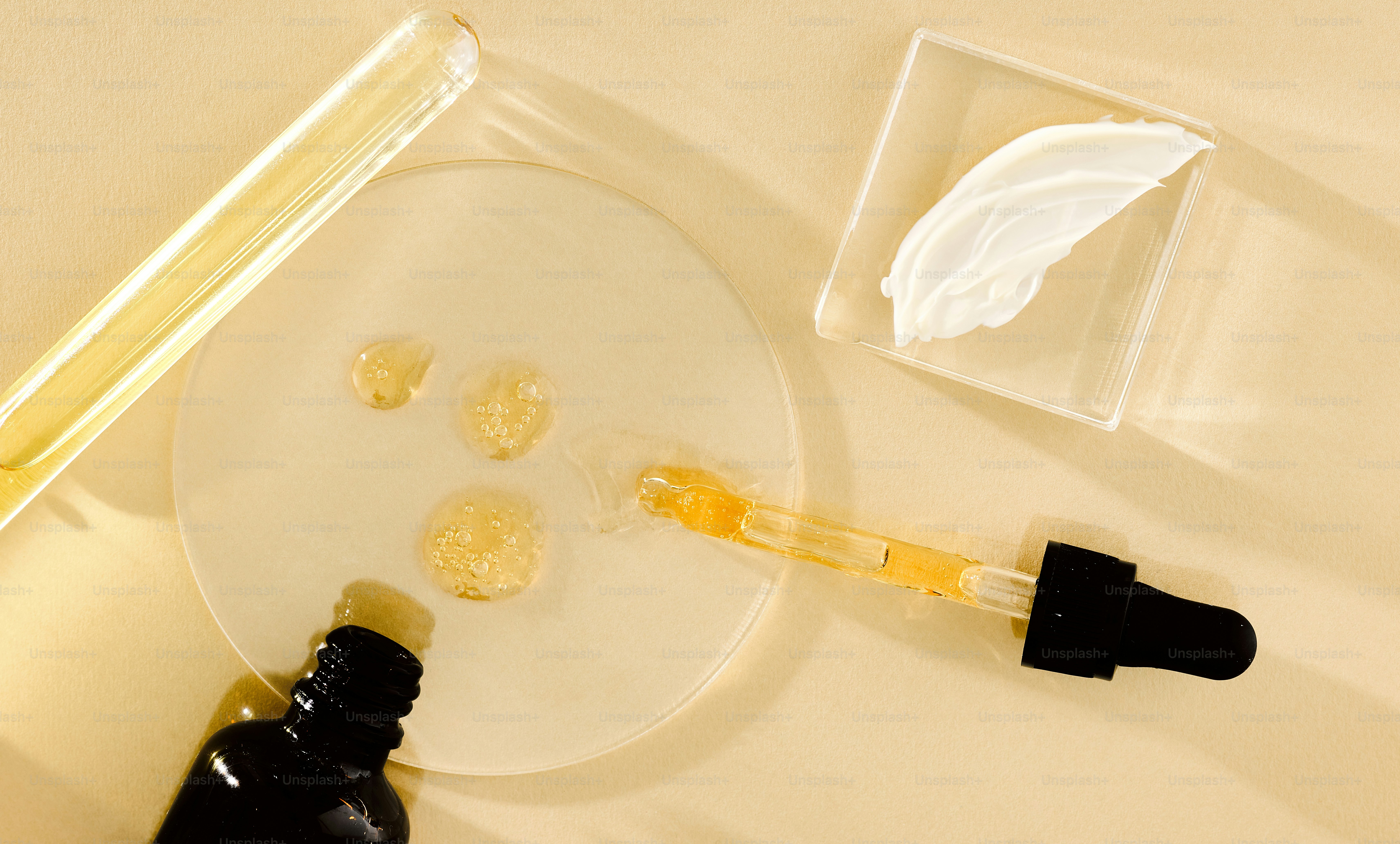 Dropper with serum and skincare products on surface