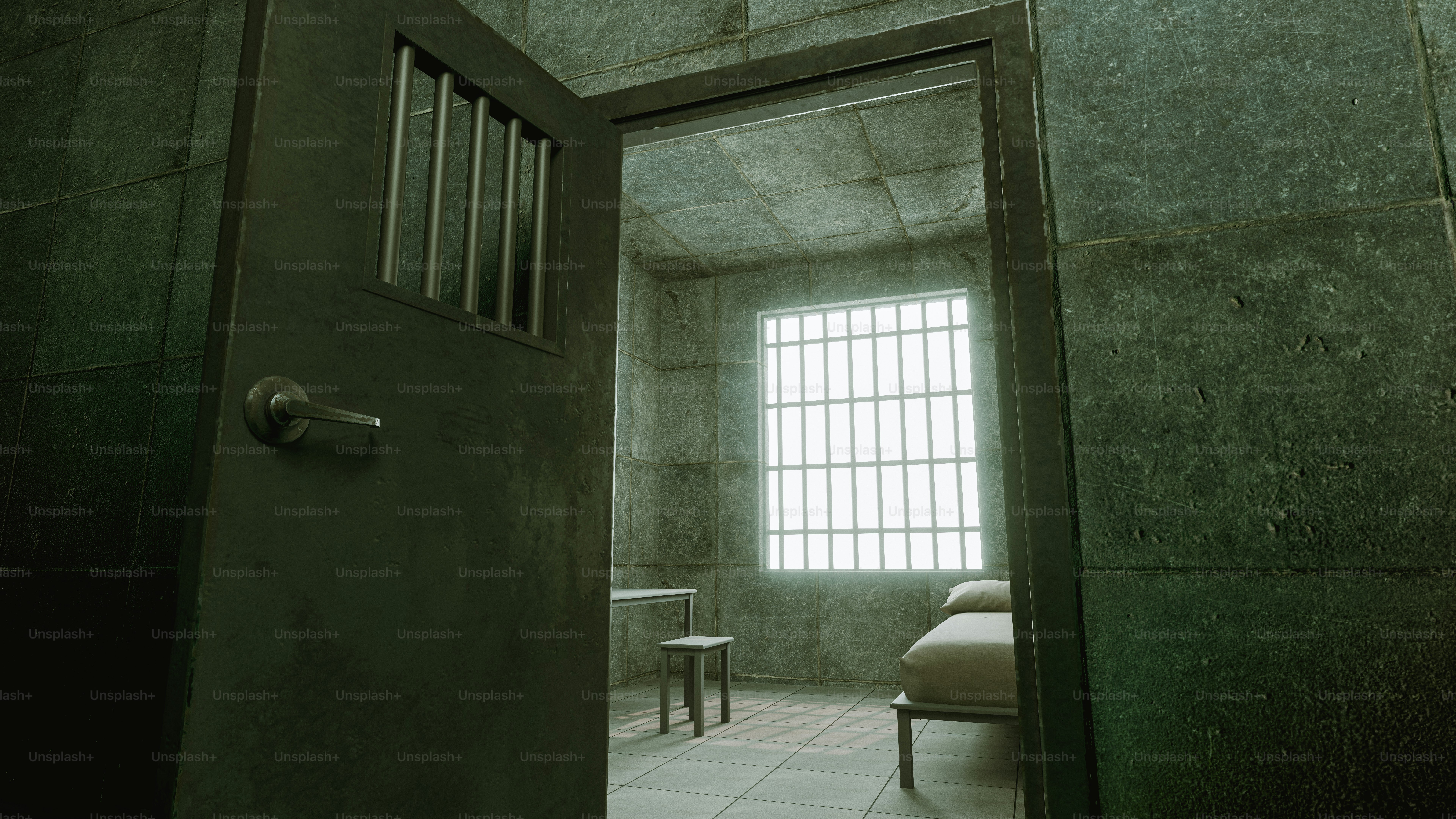 An empty prison cell with a bed and chair.