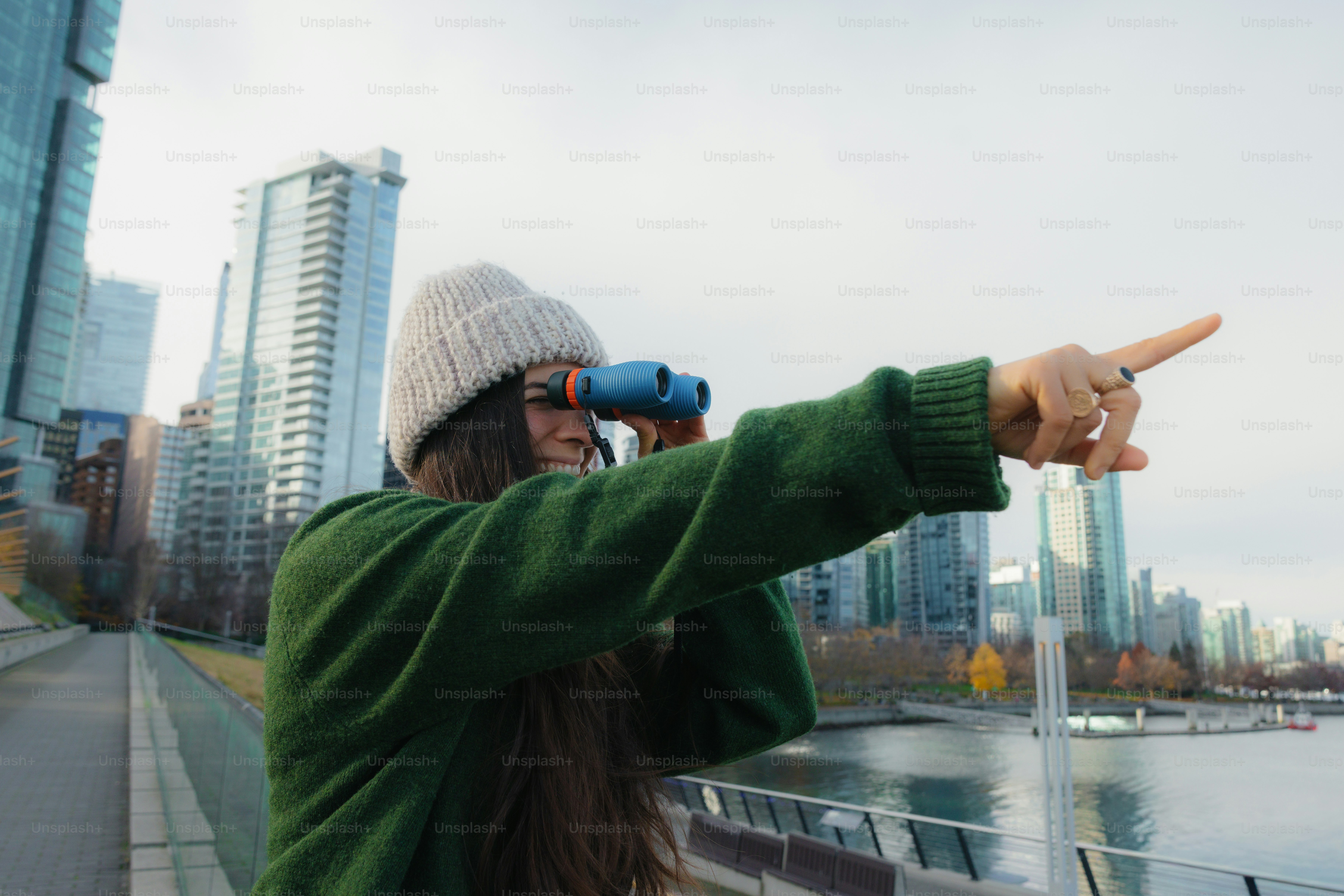 Mujer mirando a través de prismáticos en un entorno urbano del litoral