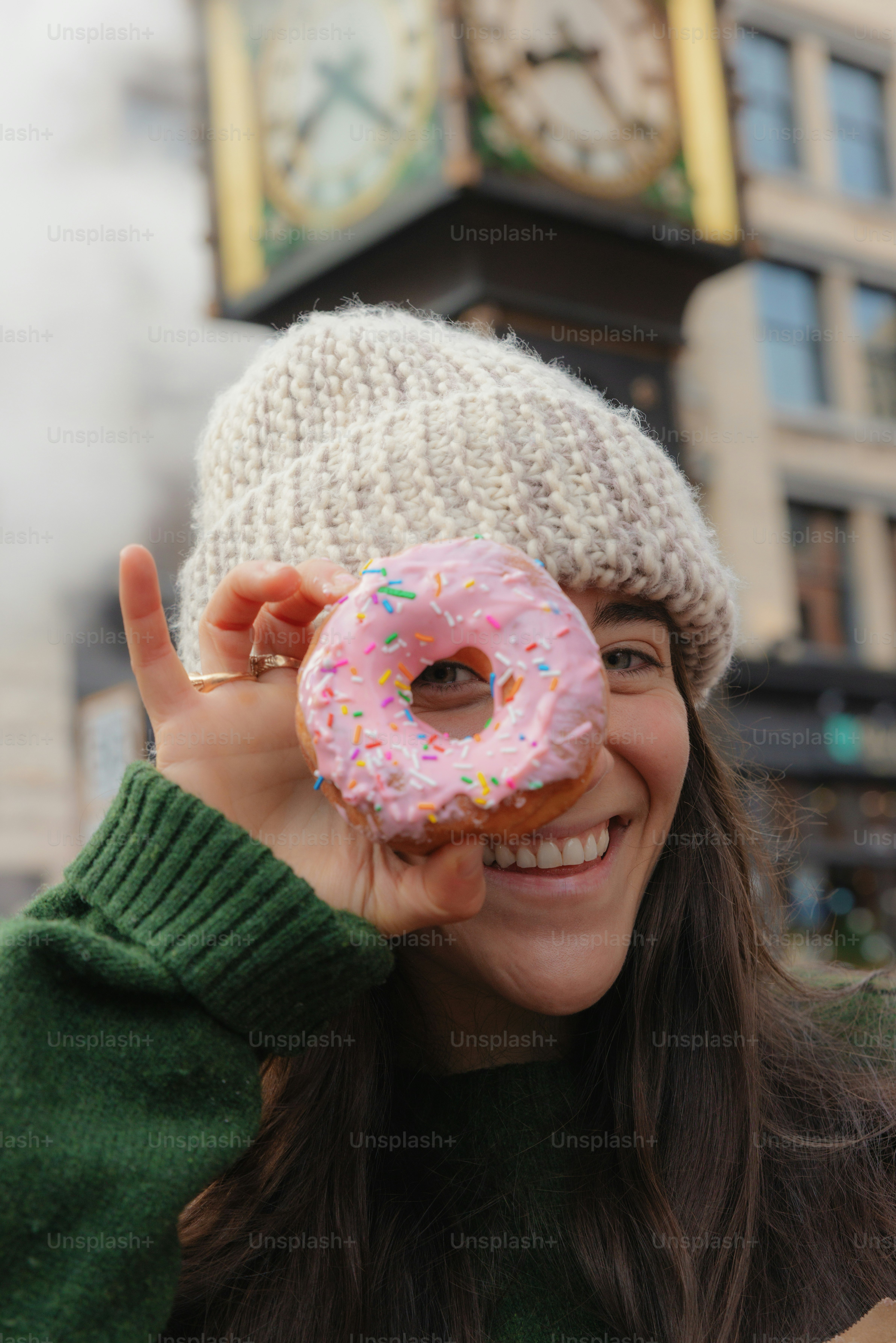 Woman holding pink frosted donut over eye
