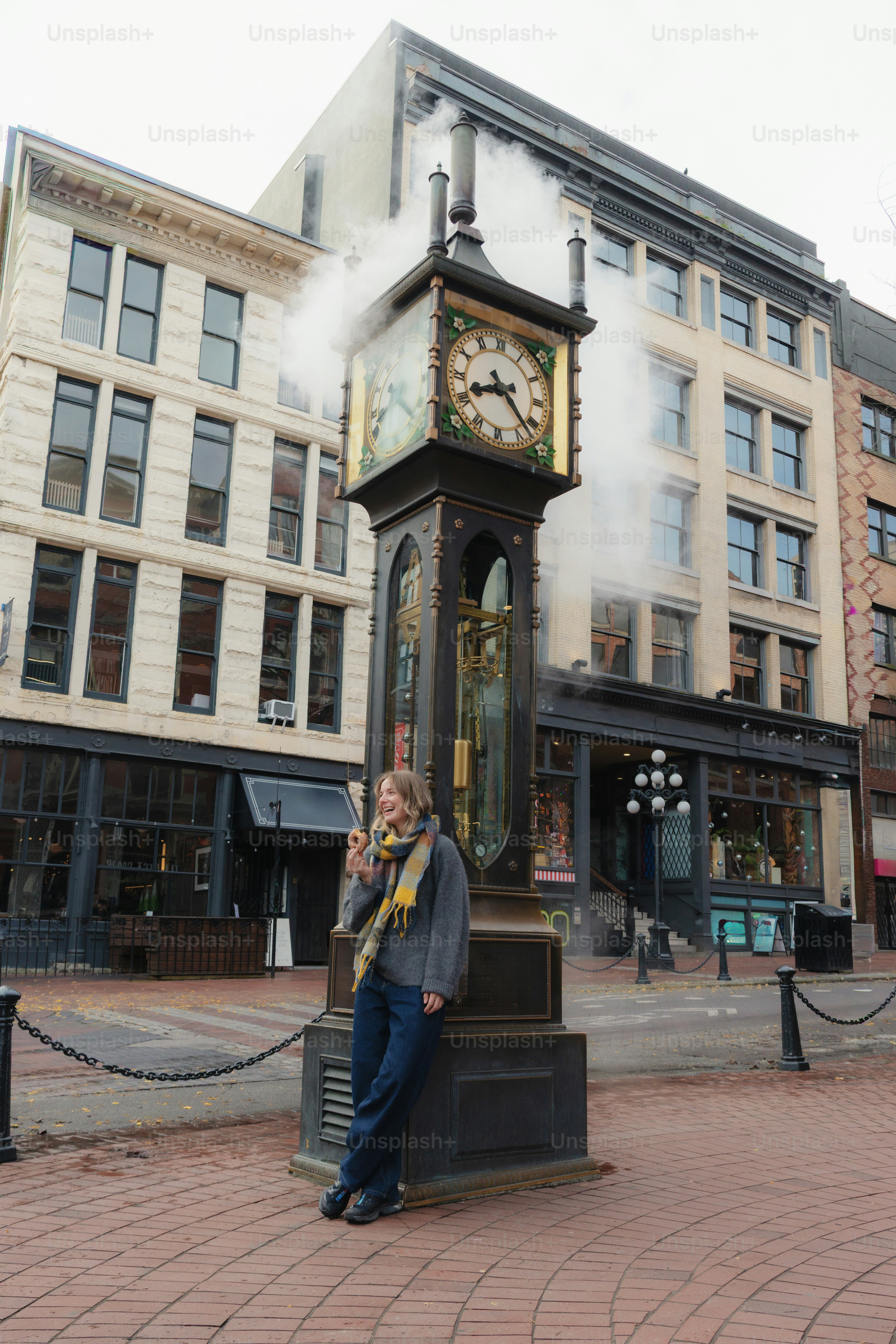 Woman leaning on a steam clock in a city.