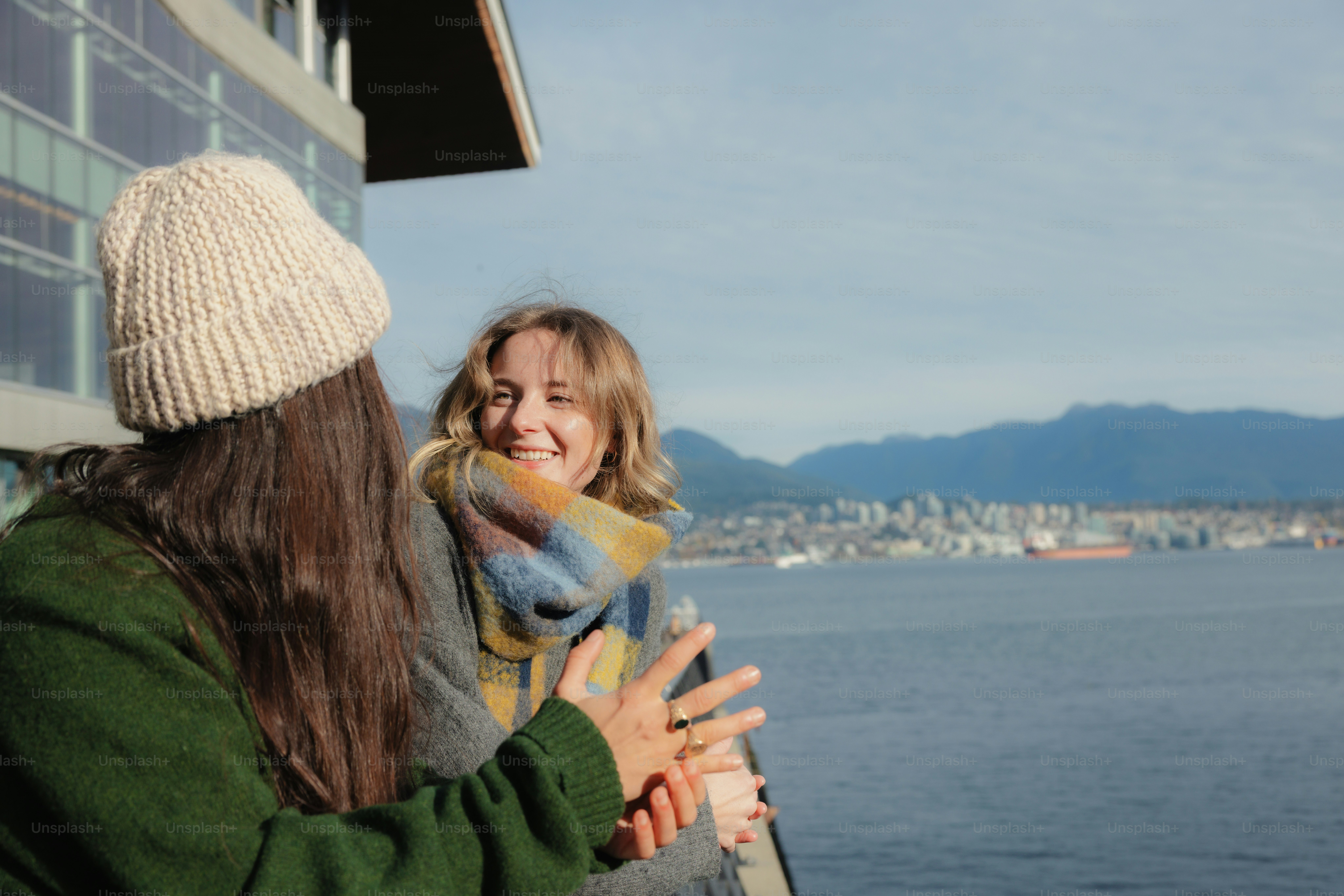 Two women talking on a balcony overlooking the water.
