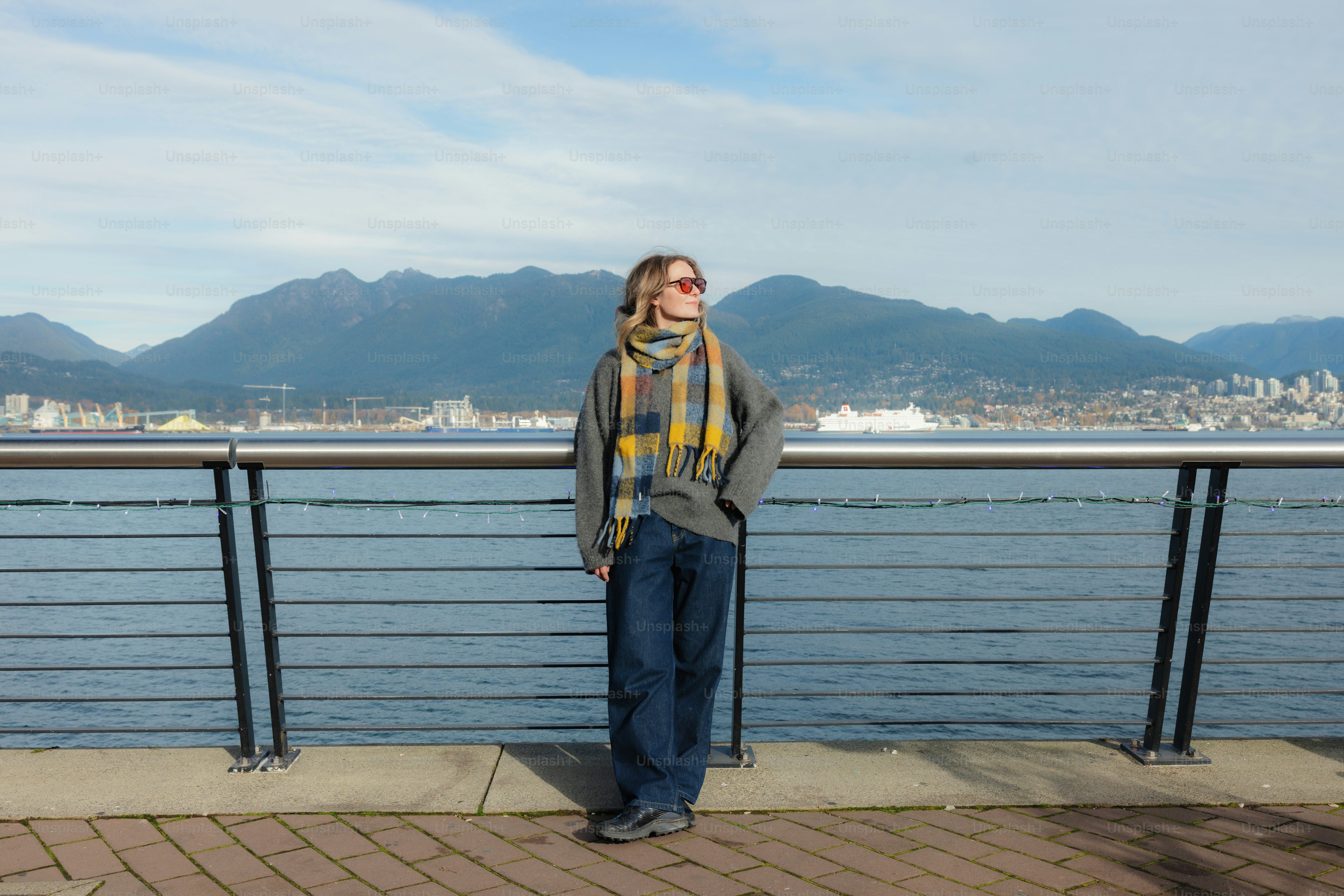 Woman standing by the water with mountains behind