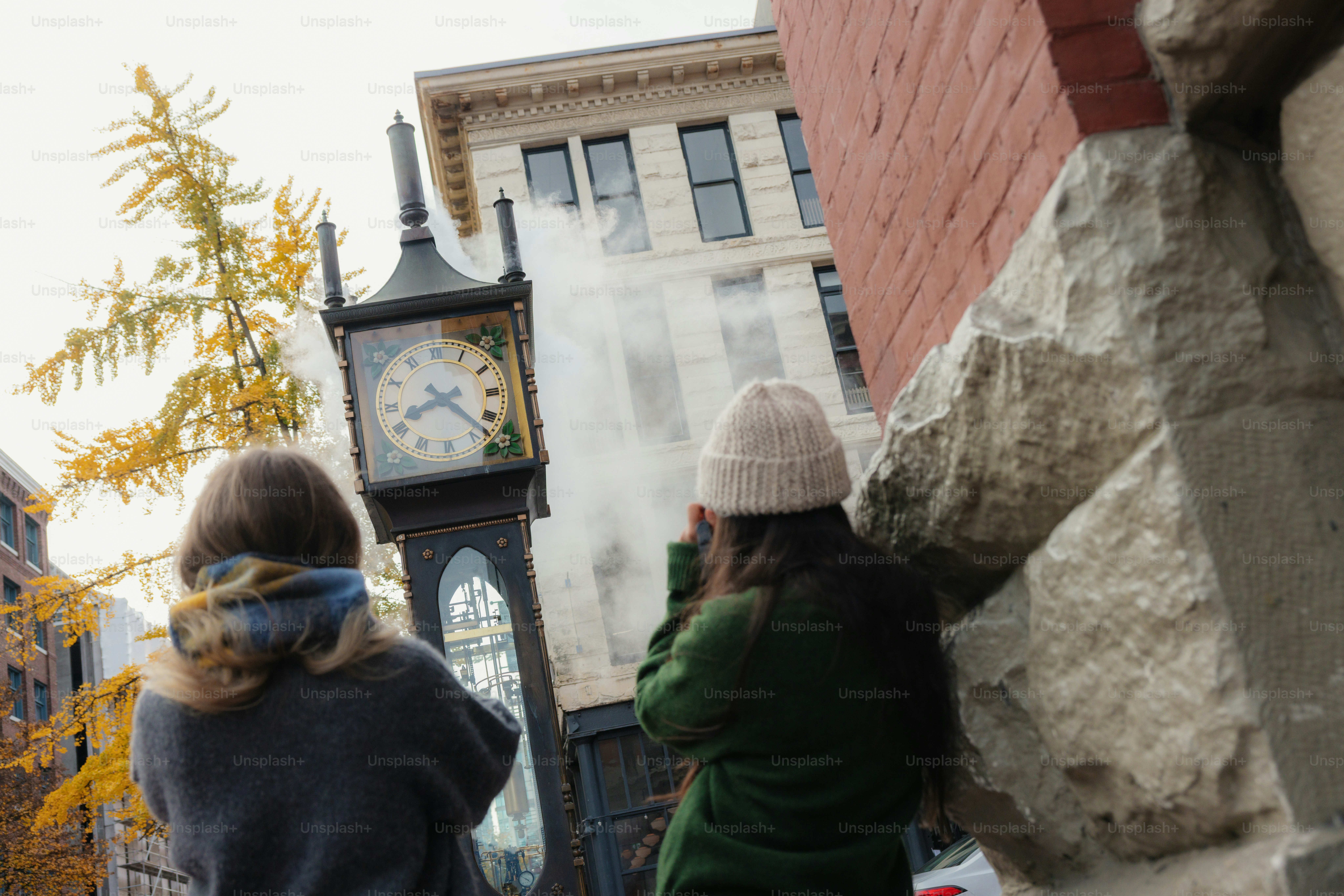 People watch steam erupt from a clock tower.