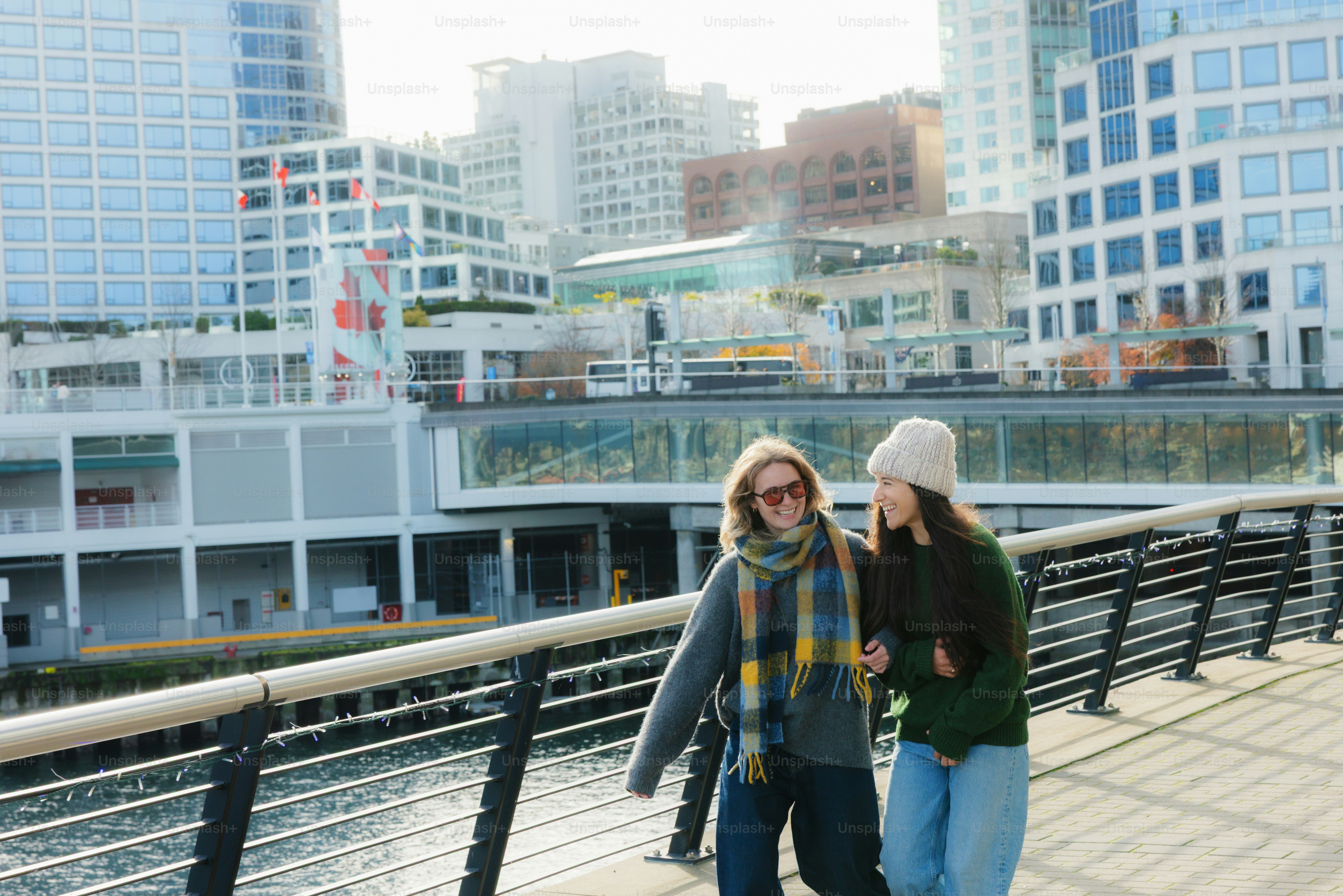 Two women walking on a waterfront promenade.