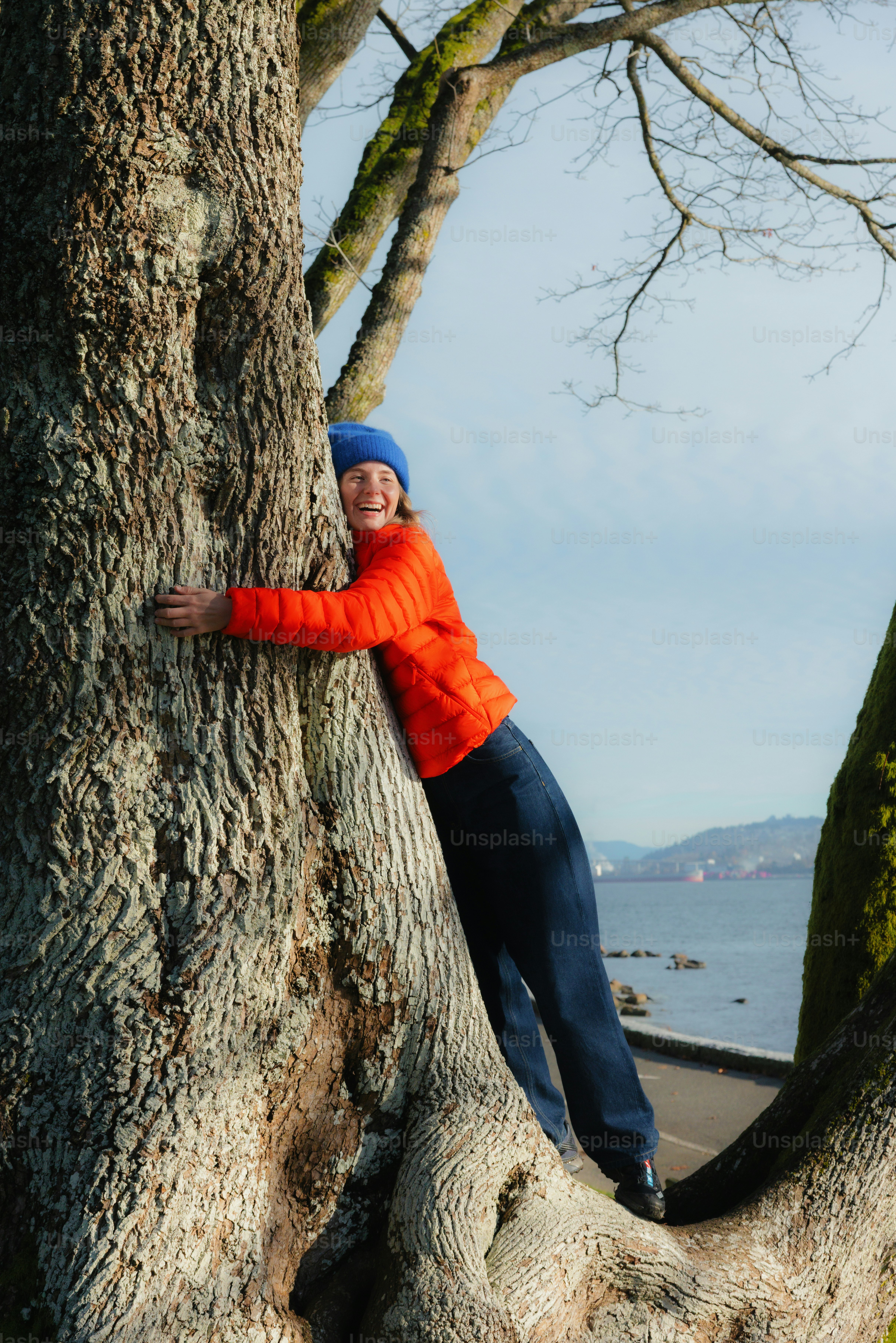 Woman hugging a large tree by the water