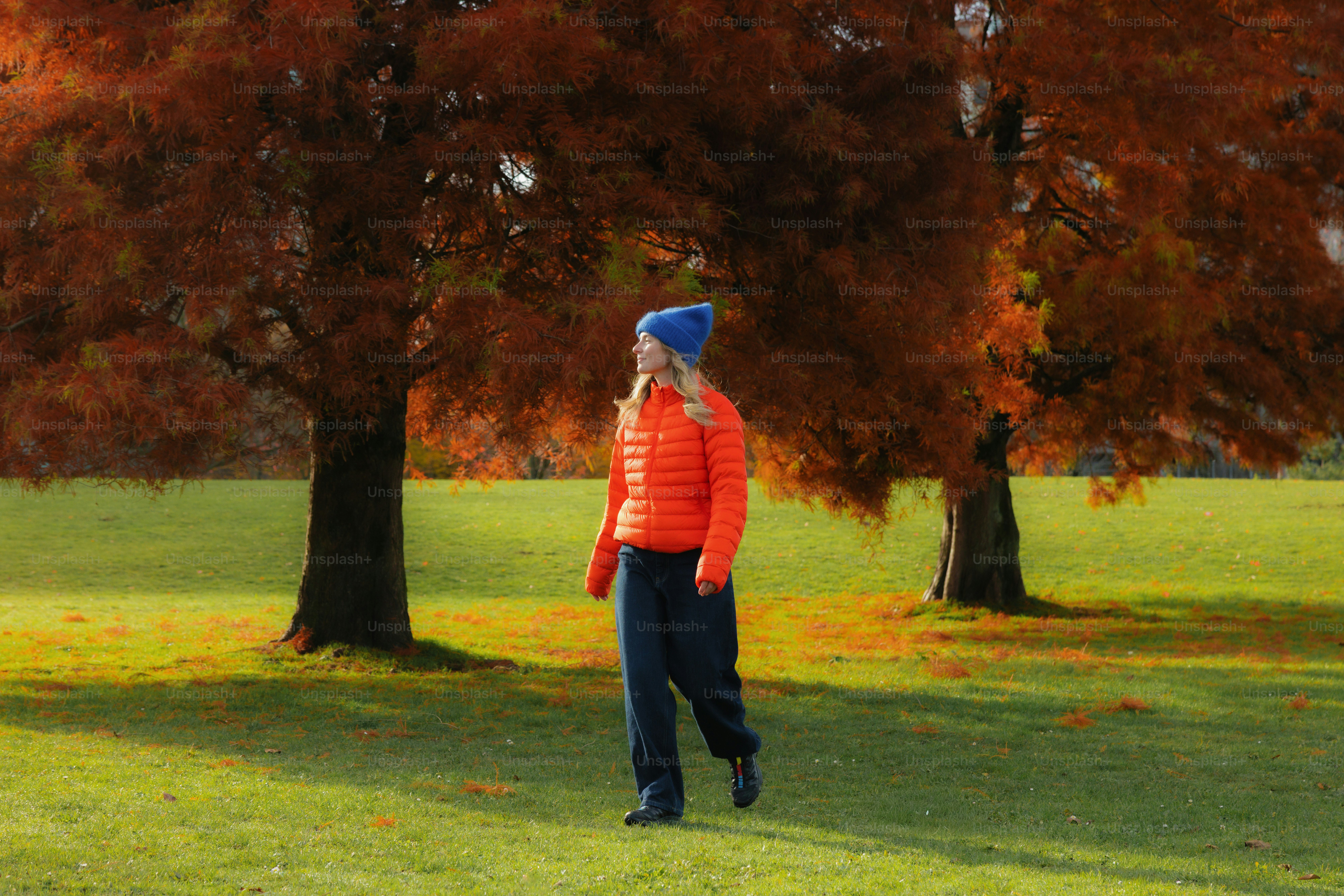 Woman walking in a park with autumn trees.