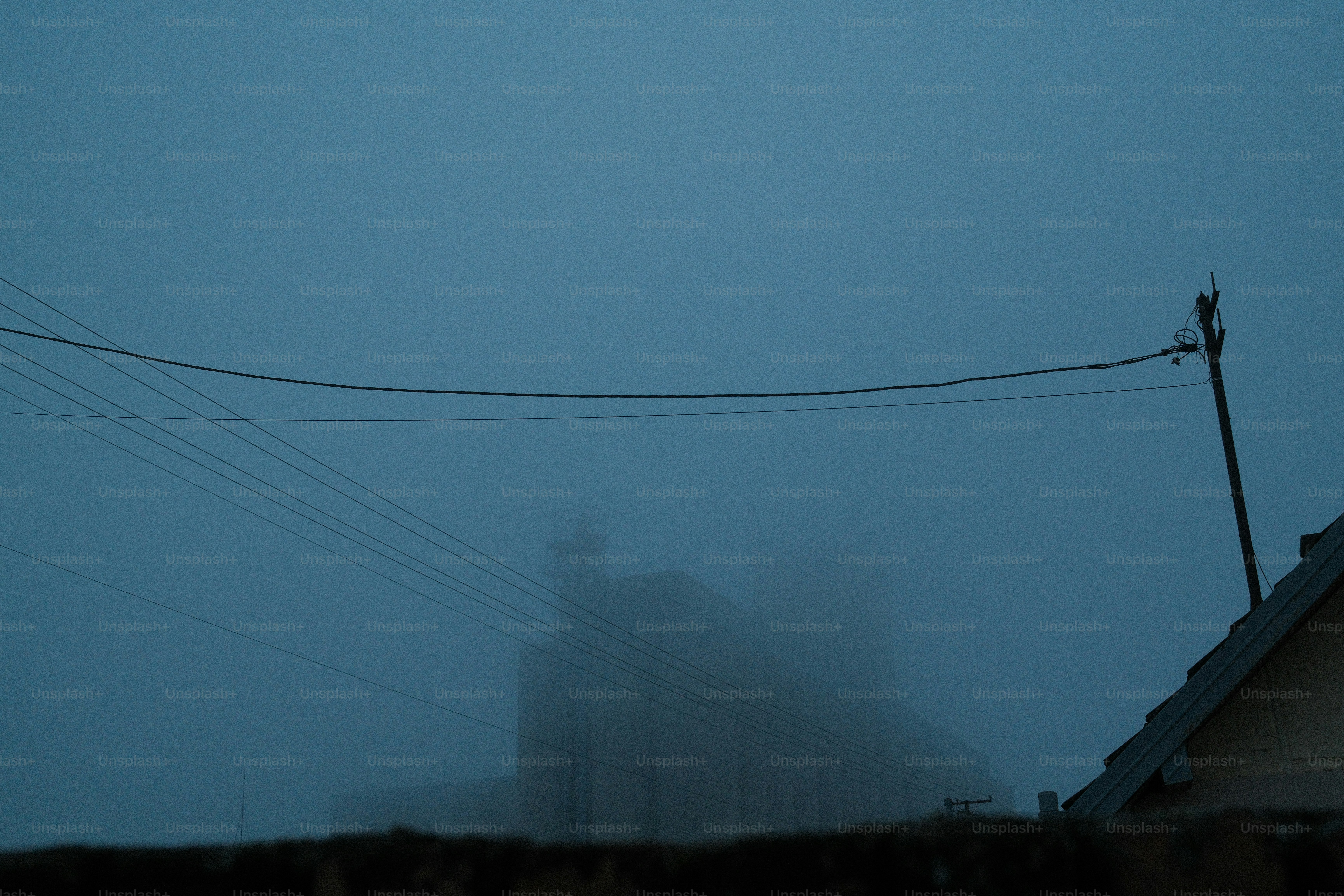 A building shrouded in thick fog with power lines.