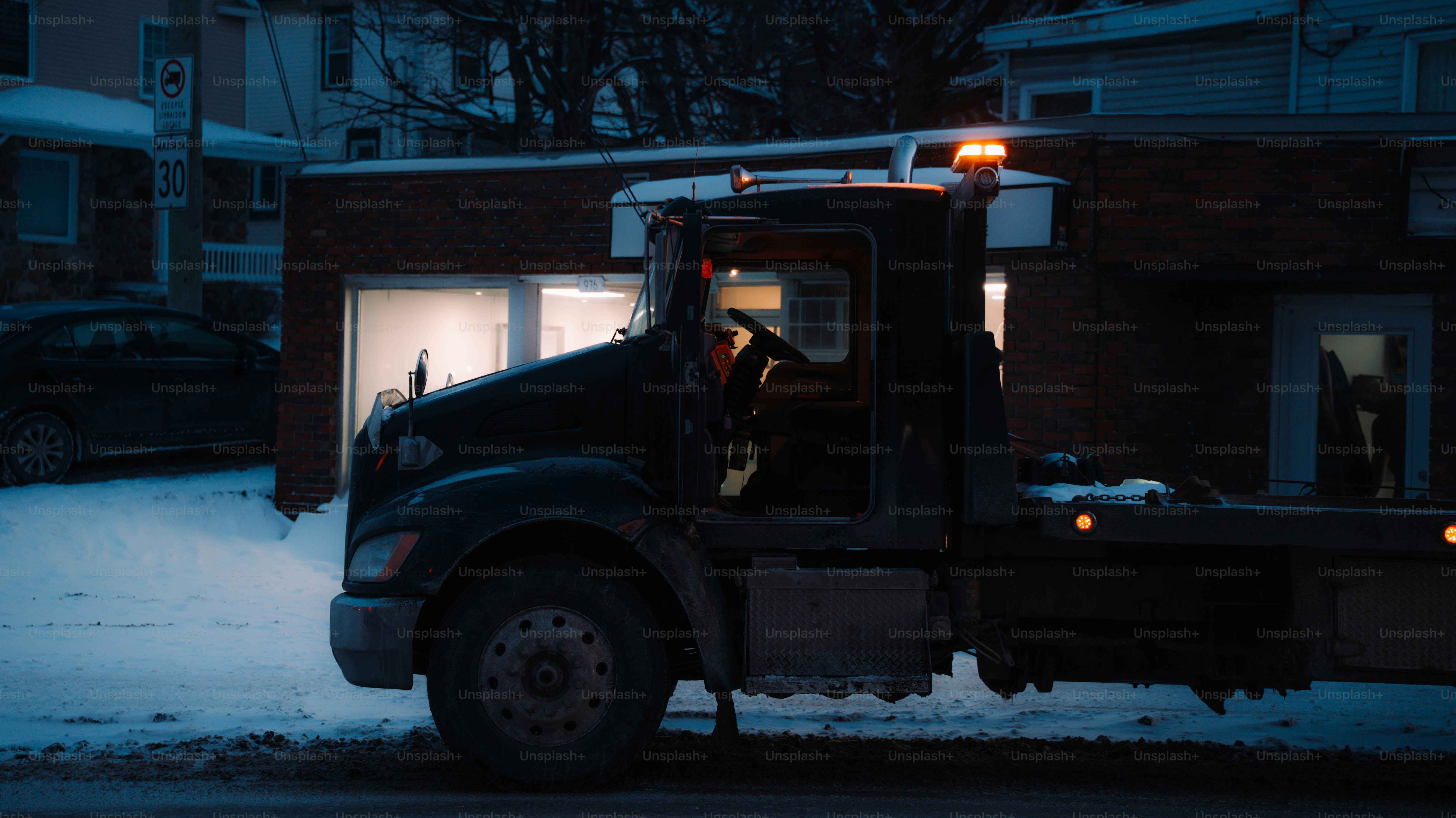 Tow truck with flashing lights on a snowy street.