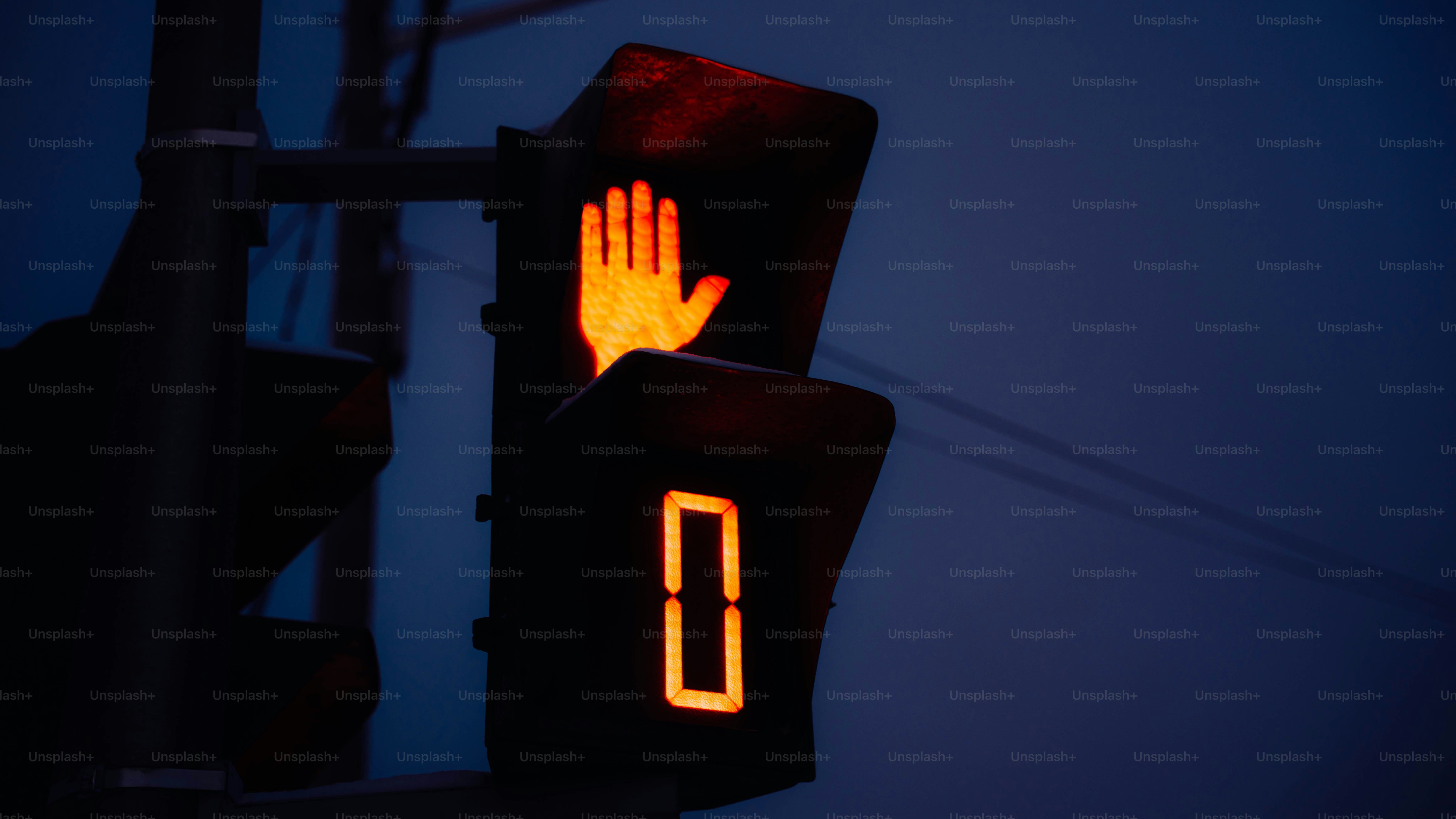 Pedestrian signal showing hand and countdown timer at dusk