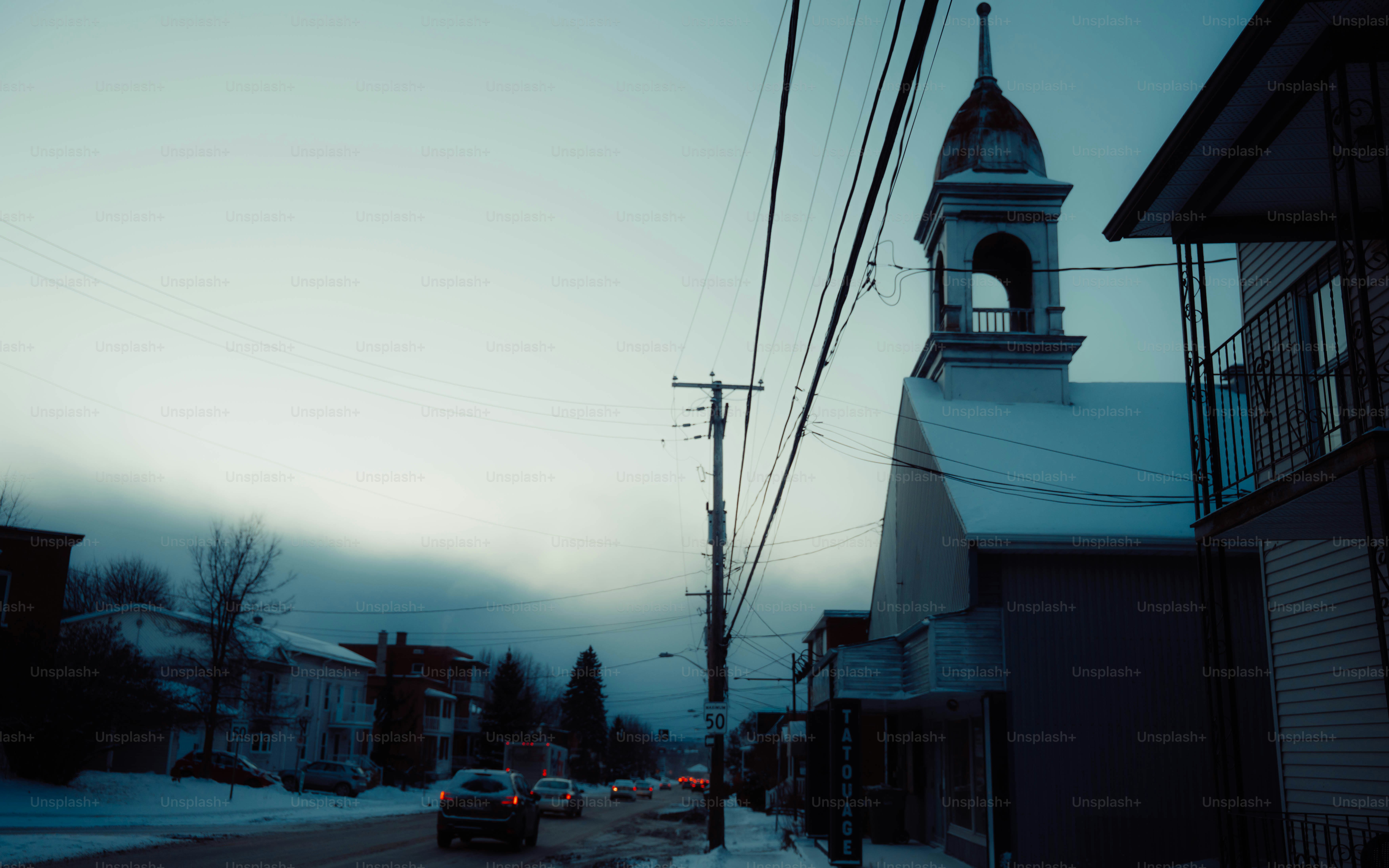 Snowy street with a church and power lines.