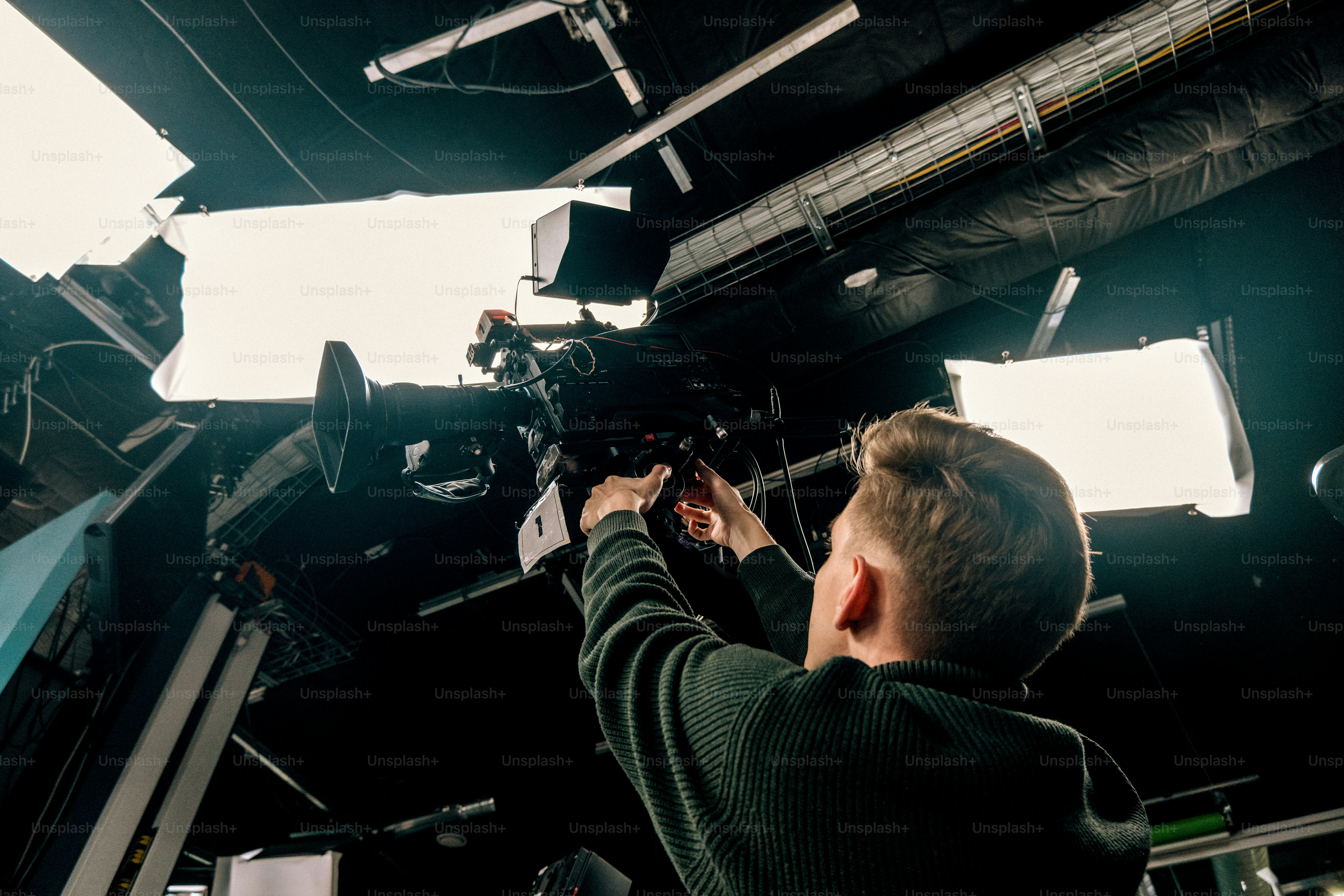 Filmmaker operating professional camera with studio lighting